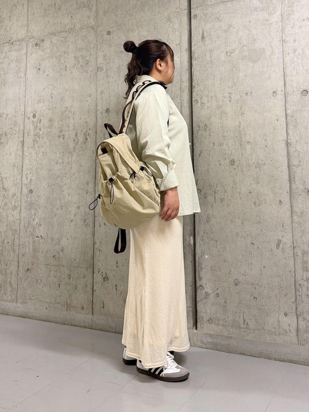 グリーン系のシャツ/ブラウス、ホワイト系のスカート、ベージュ系のバックパック/リュックを着用したレディースの春コーディネートの2枚目の写真