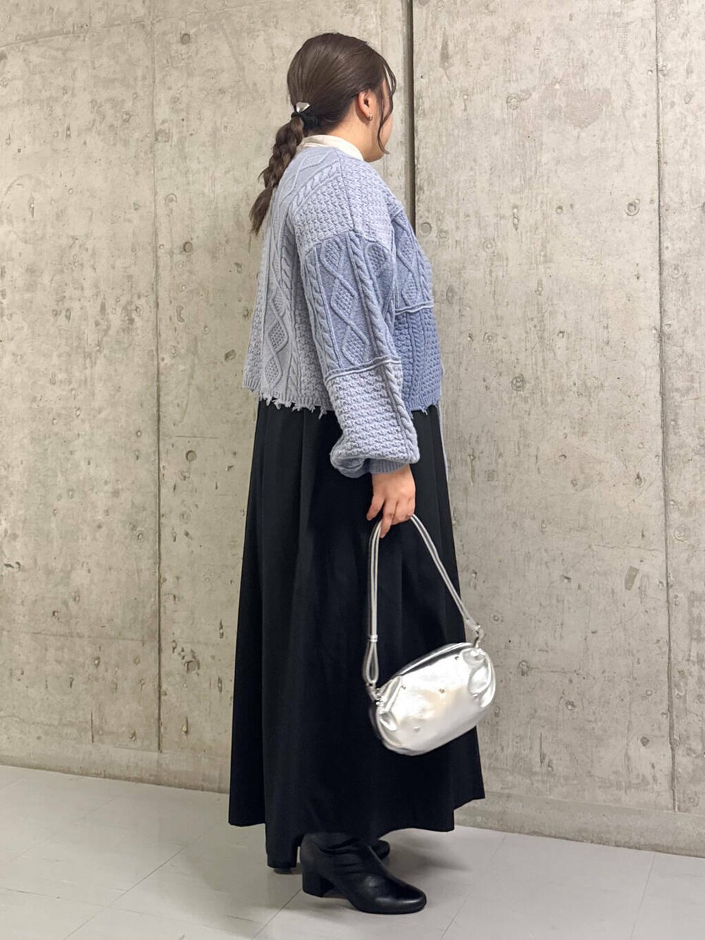 ブラック系のブーツ、ブラック系のワンピース、シルバー系のショルダーバッグを着用したレディースの冬コーディネートの2枚目の写真