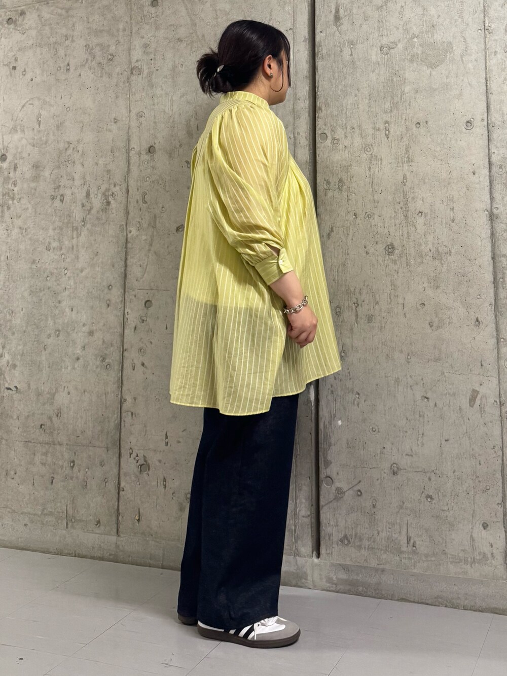 イエロー系のワンピース、ブルー系のデニムパンツを着用したレディースの夏コーディネートの2枚目の写真