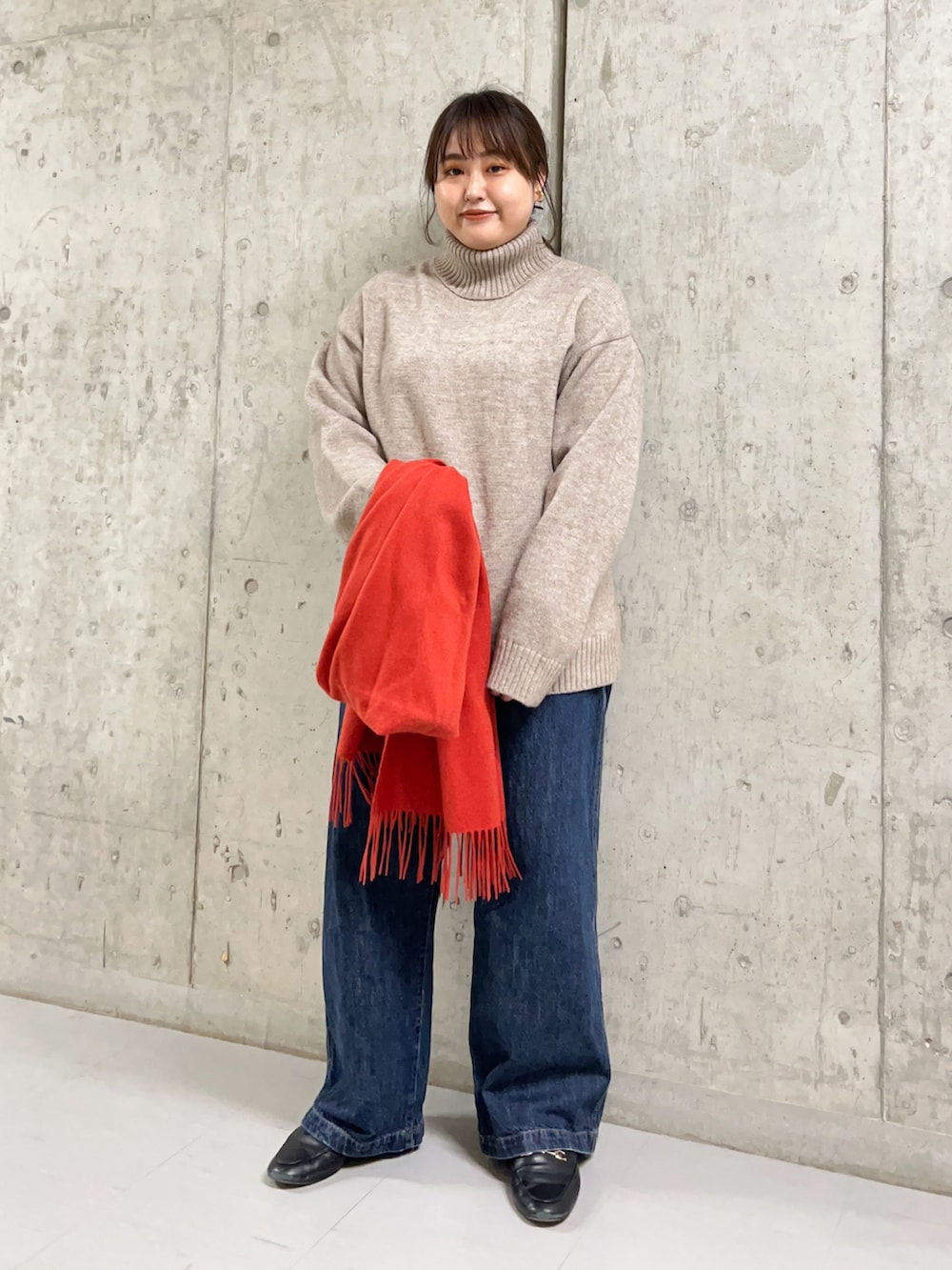 ベージュ系のニット/セーター、ブラック系のチェスターコート、オレンジ系のストール/ショールを着用したレディースの冬コーディネートの2枚目の写真