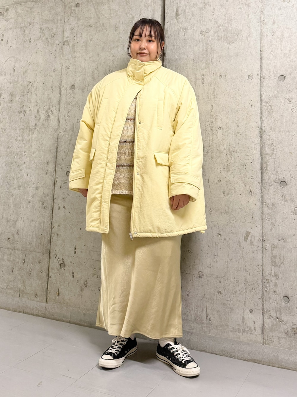 イエロー系のダウンジャケット/コート、ホワイト系のニット/セーター、パープル系のスカートを着用したレディースの秋コーディネートの3枚目の写真