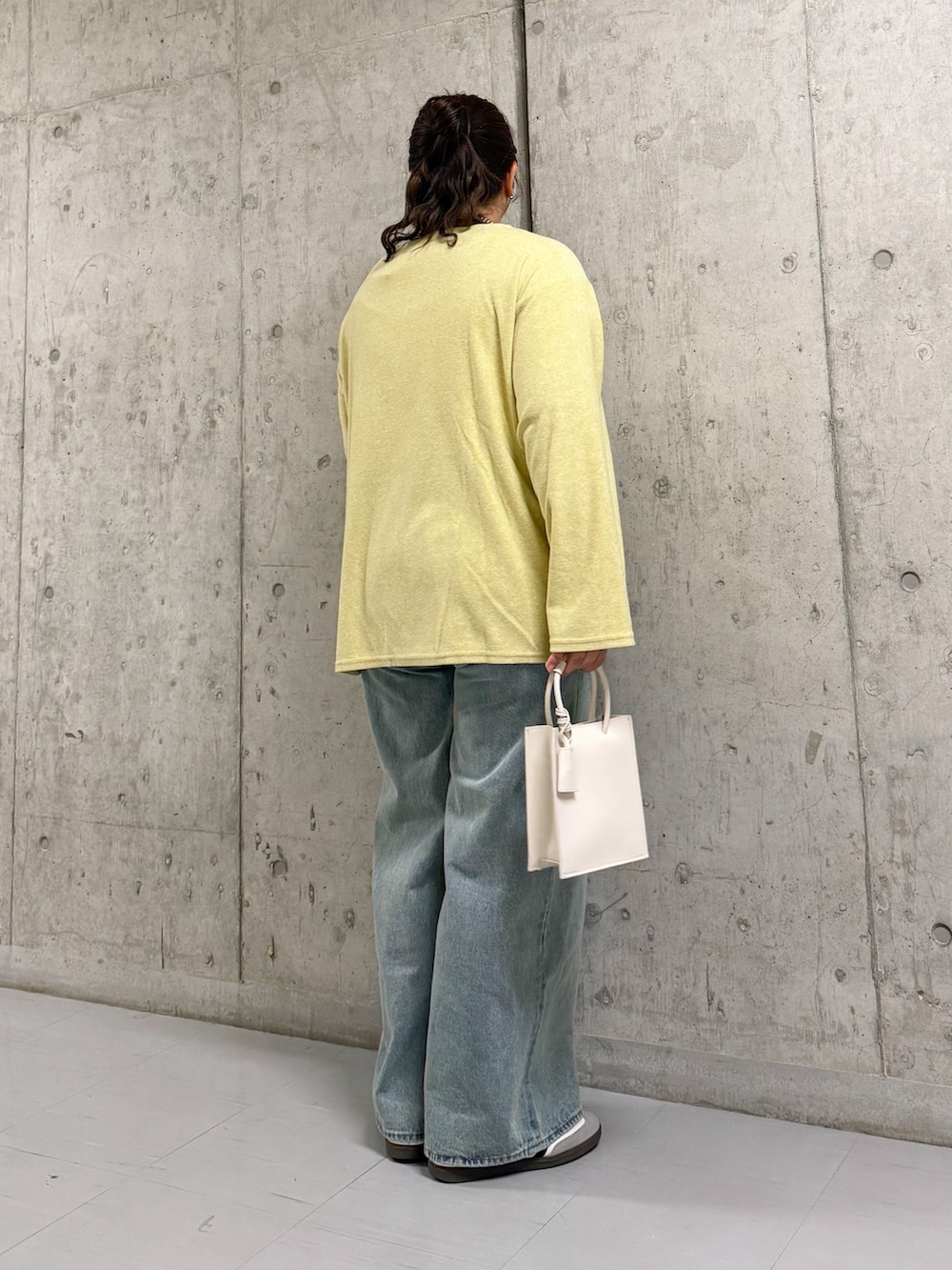 イエロー系のTシャツ/カットソー、ブルー系のデニムパンツ、ホワイト系のハンドバッグを着用したレディースの春コーディネートの3枚目の写真