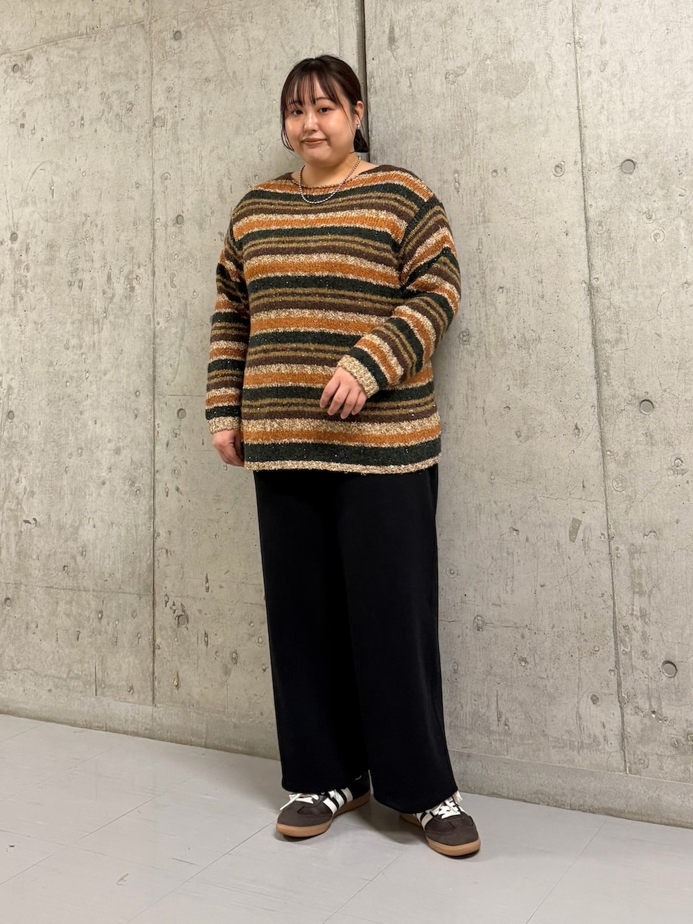 ブラック系のステンカラーコート、ブラウン系のニット/セーター、ブラック系のその他パンツを着用したレディースの冬コーディネートの2枚目の写真