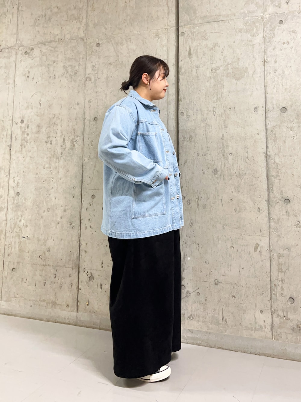 ブルー系のデニムジャケット、オレンジ系のニット/セーター、ブラック系のサロペット/オーバーオールを着用したレディースの冬コーディネートの2枚目の写真