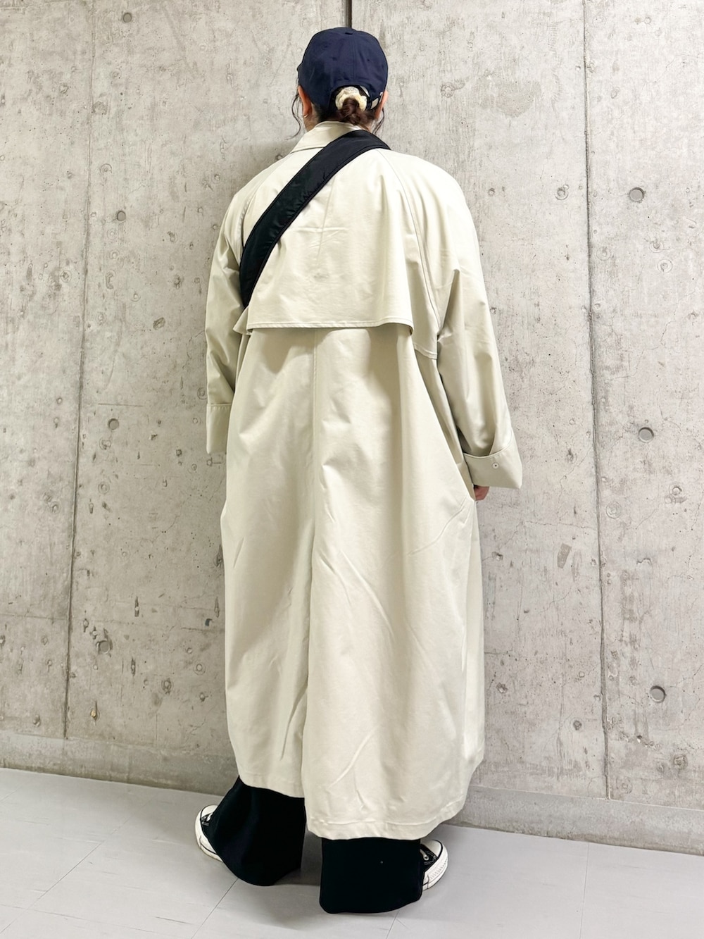 グレー系のステンカラーコート、ブルー系のニット/セーター、ブラック系のショルダーバッグを着用したレディースの春コーディネートの4枚目の写真