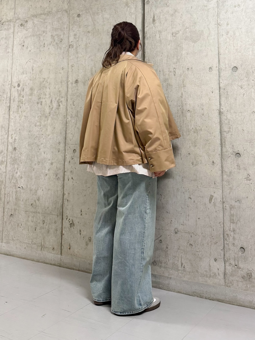 ベージュ系のステンカラーコート、ピンク系のシャツ/ブラウス、ブルー系のデニムパンツを着用したレディースの春コーディネートの3枚目の写真