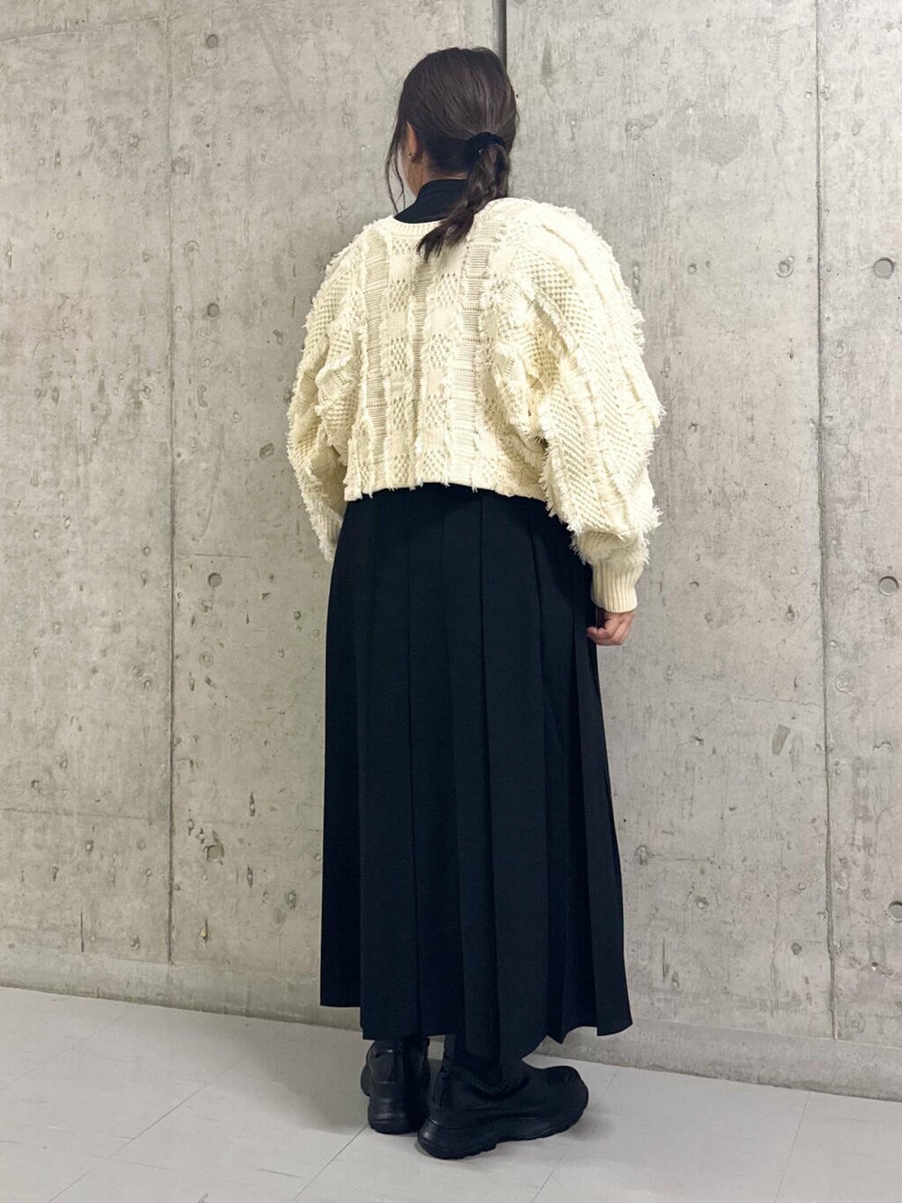 ブラック系のブーツ、ホワイト系のカーディガン/ボレロ、ブラック系のワンピースを着用したレディースの冬コーディネートの3枚目の写真