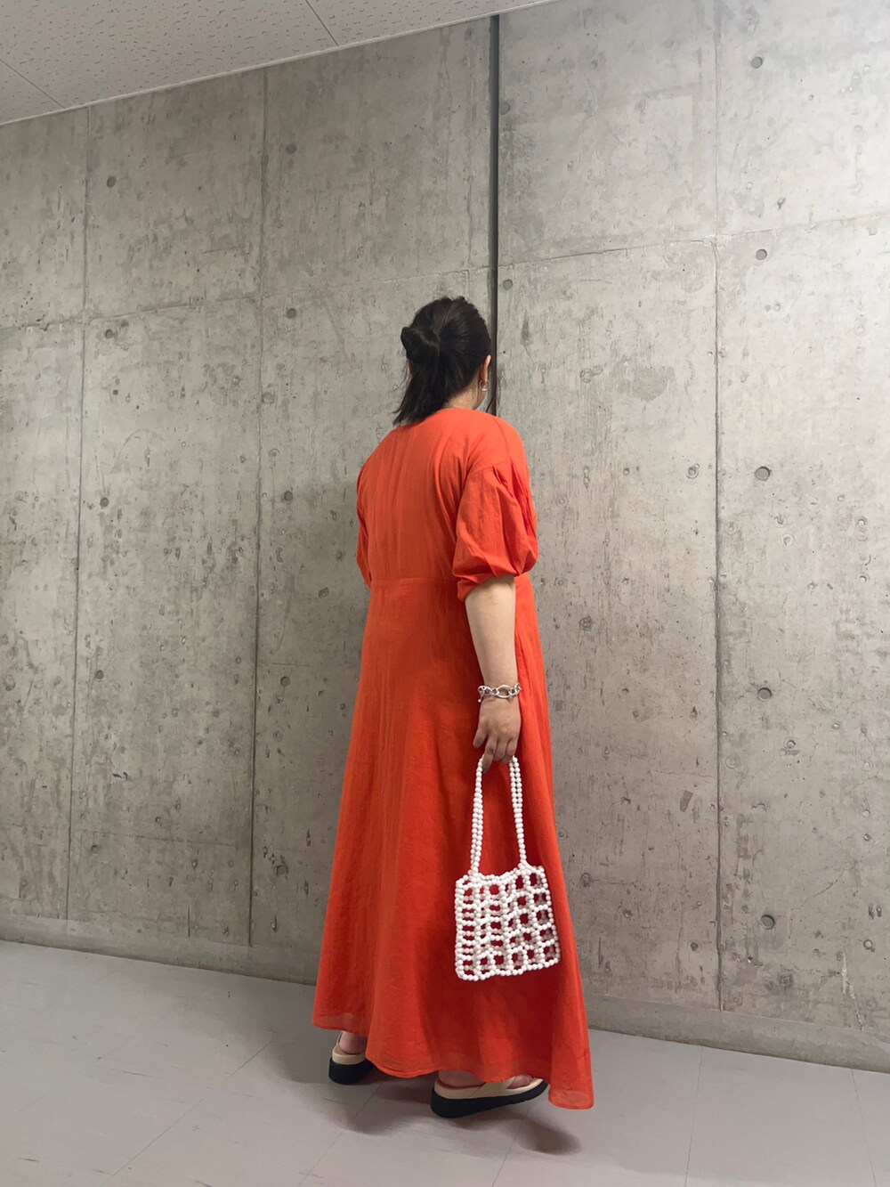 ホワイト系のサンダル、ホワイト系のハンドバッグ、オレンジ系のワンピースを着用したレディースの秋コーディネートの2枚目の写真