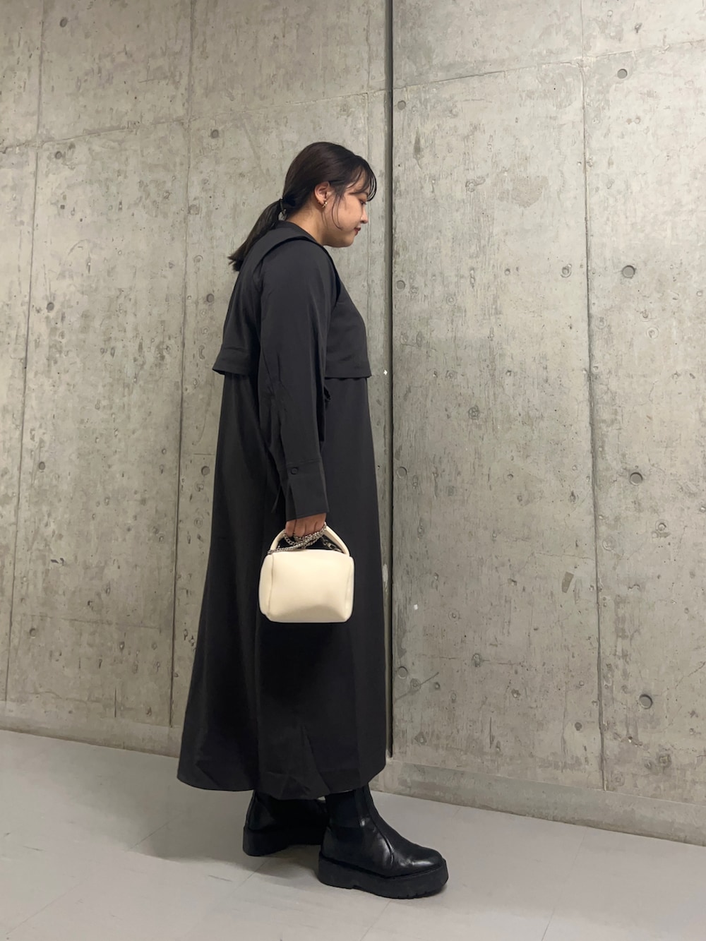 グレー系のワンピース、ホワイト系のハンドバッグを着用したレディースの秋コーディネートの2枚目の写真