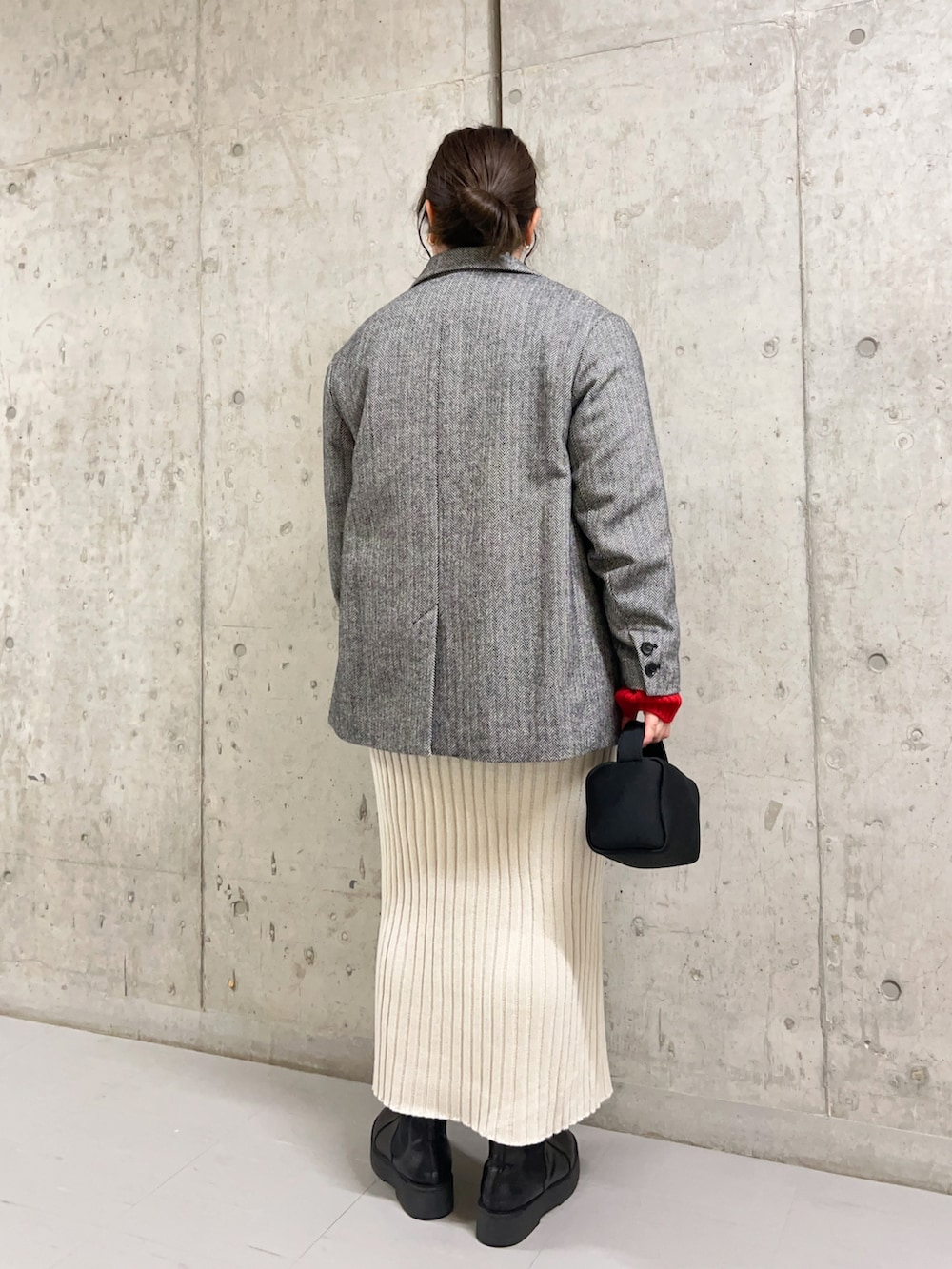 レッド系のニット/セーター、ブラック系のその他アウター、ベージュ系のスカートを着用したレディースの冬コーディネートの3枚目の写真