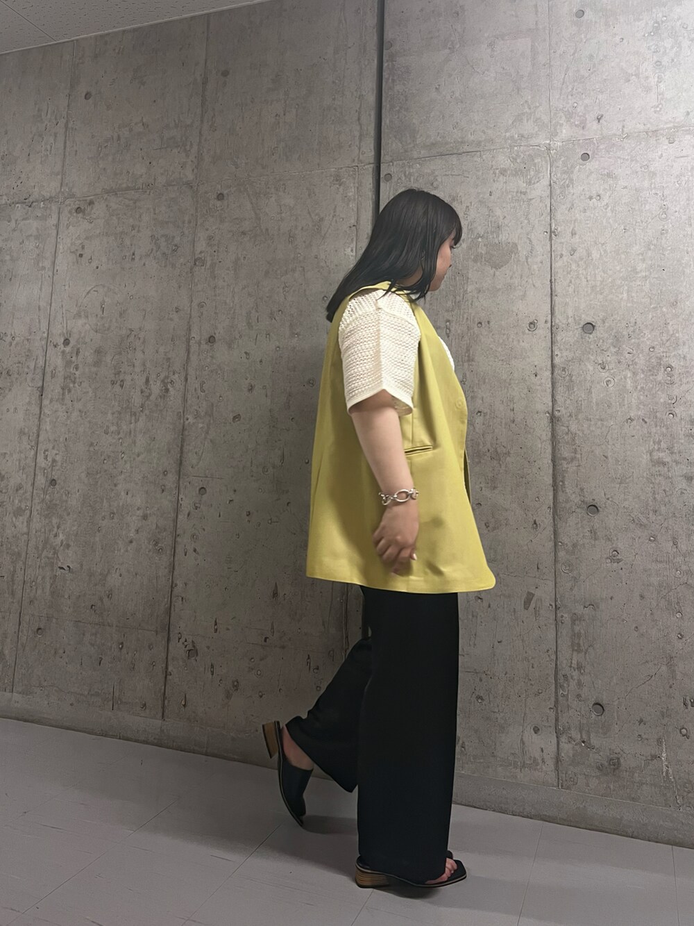ホワイト系のシャツ/ブラウス、イエロー系のベスト、ブラック系のサンダルを着用したレディースの夏コーディネートの2枚目の写真