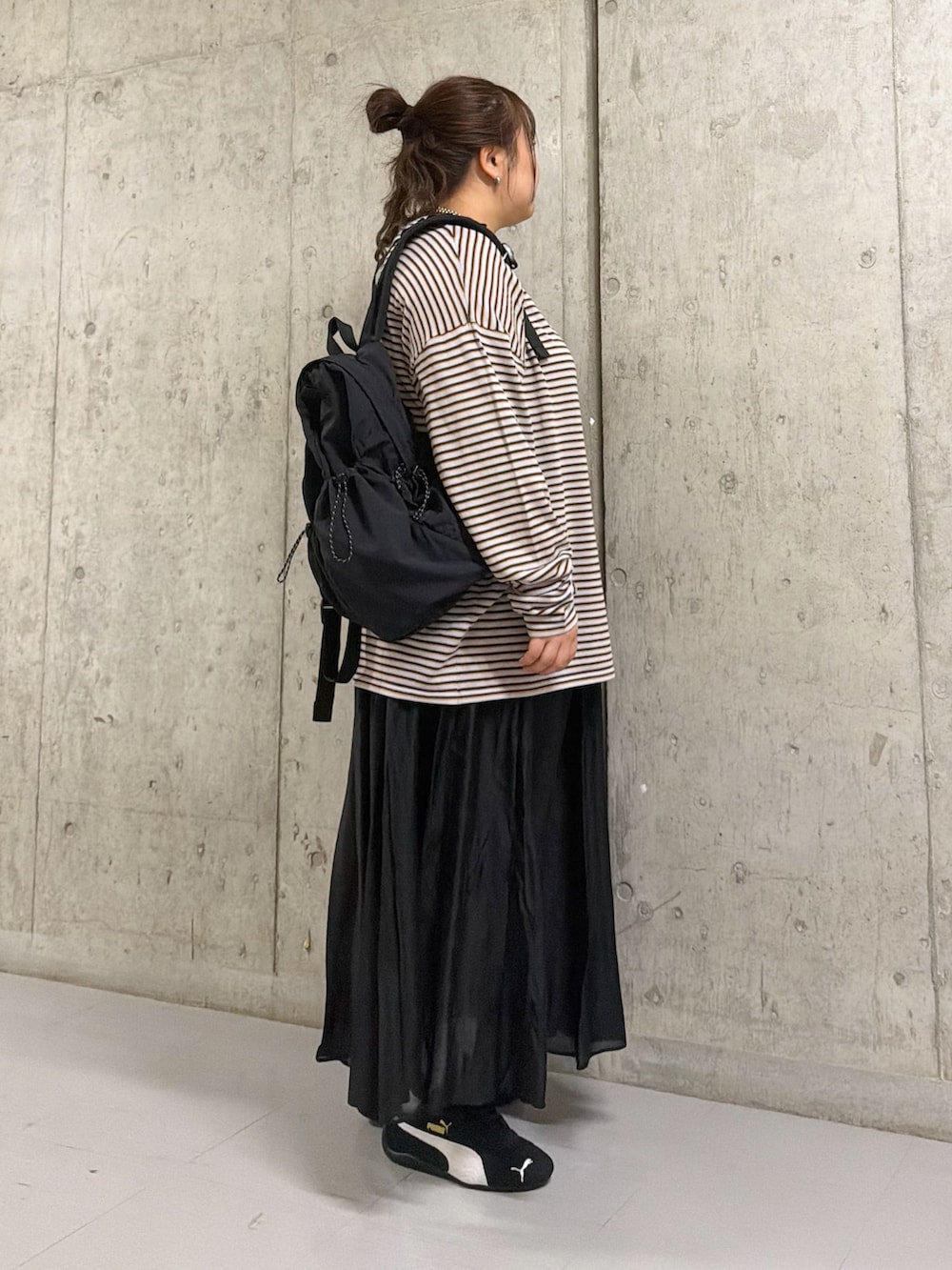 グレー系のニット/セーター、ブラック系のバックパック/リュック、ブラック系のスカートを着用したレディースの春コーディネートの2枚目の写真