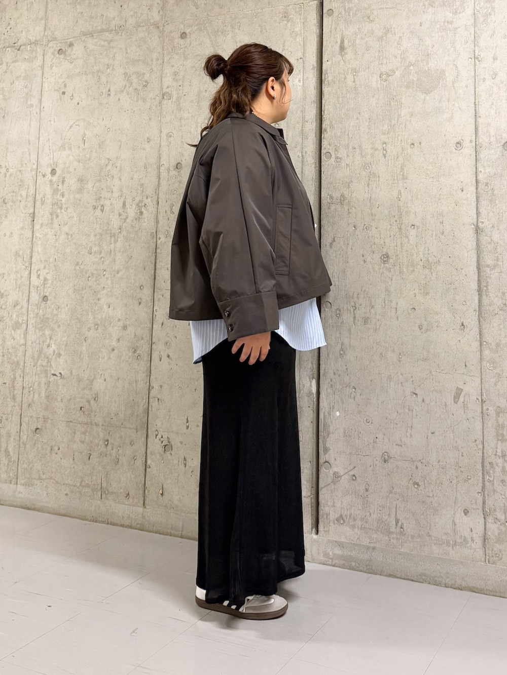 グレー系のステンカラーコート、ブルー系のシャツ/ブラウス、ブラック系のスカートを着用したレディースの冬コーディネートの2枚目の写真