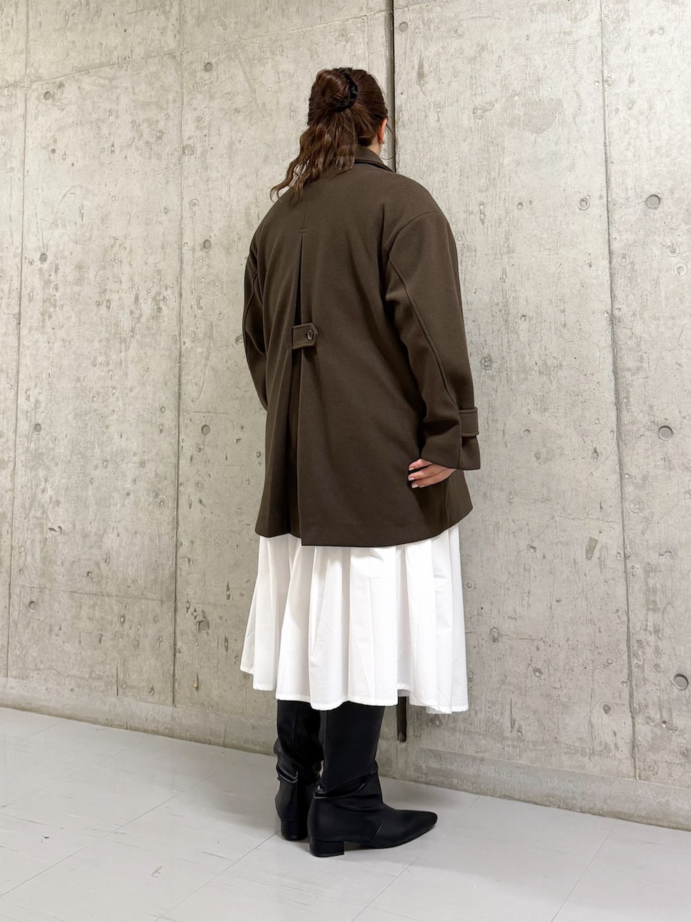 ブラウン系のその他アウター、ホワイト系のスカート、ブラック系のブーツを着用したレディースの冬コーディネートの2枚目の写真