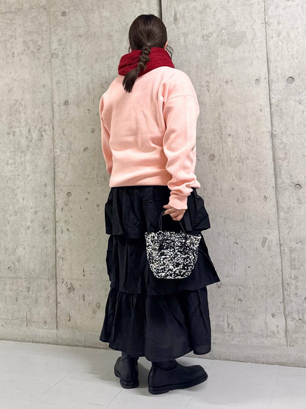 シルバー系のショルダーバッグ、ブラック系のブーツ、ブラック系のスカートを着用したレディースの冬コーディネートの2枚目の写真