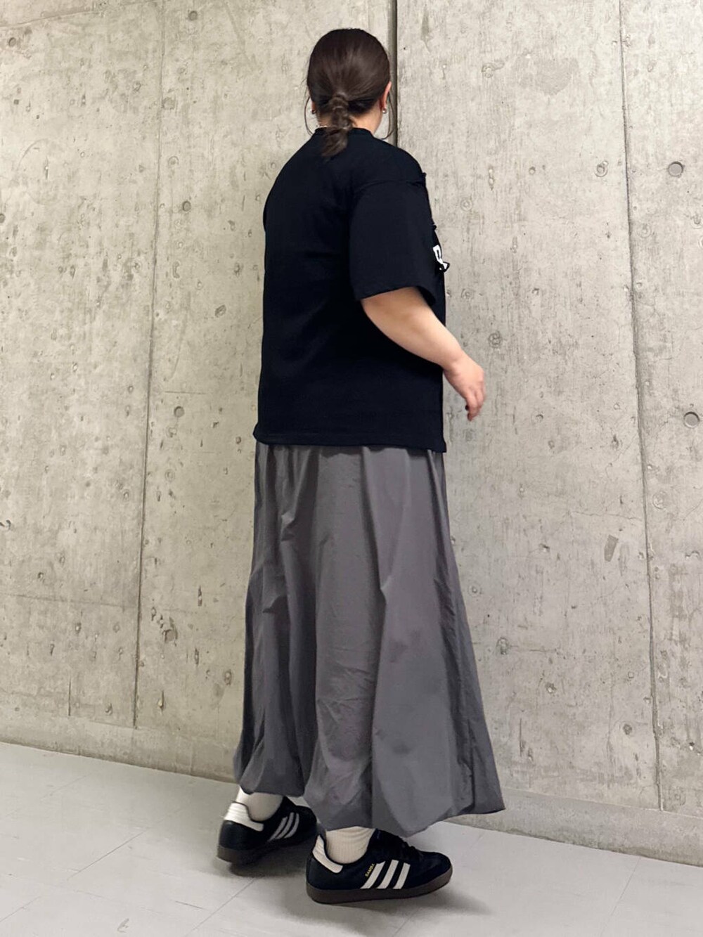 グレー系のスカート、ブラック系のTシャツ/カットソーを着用したレディースの春コーディネートの2枚目の写真
