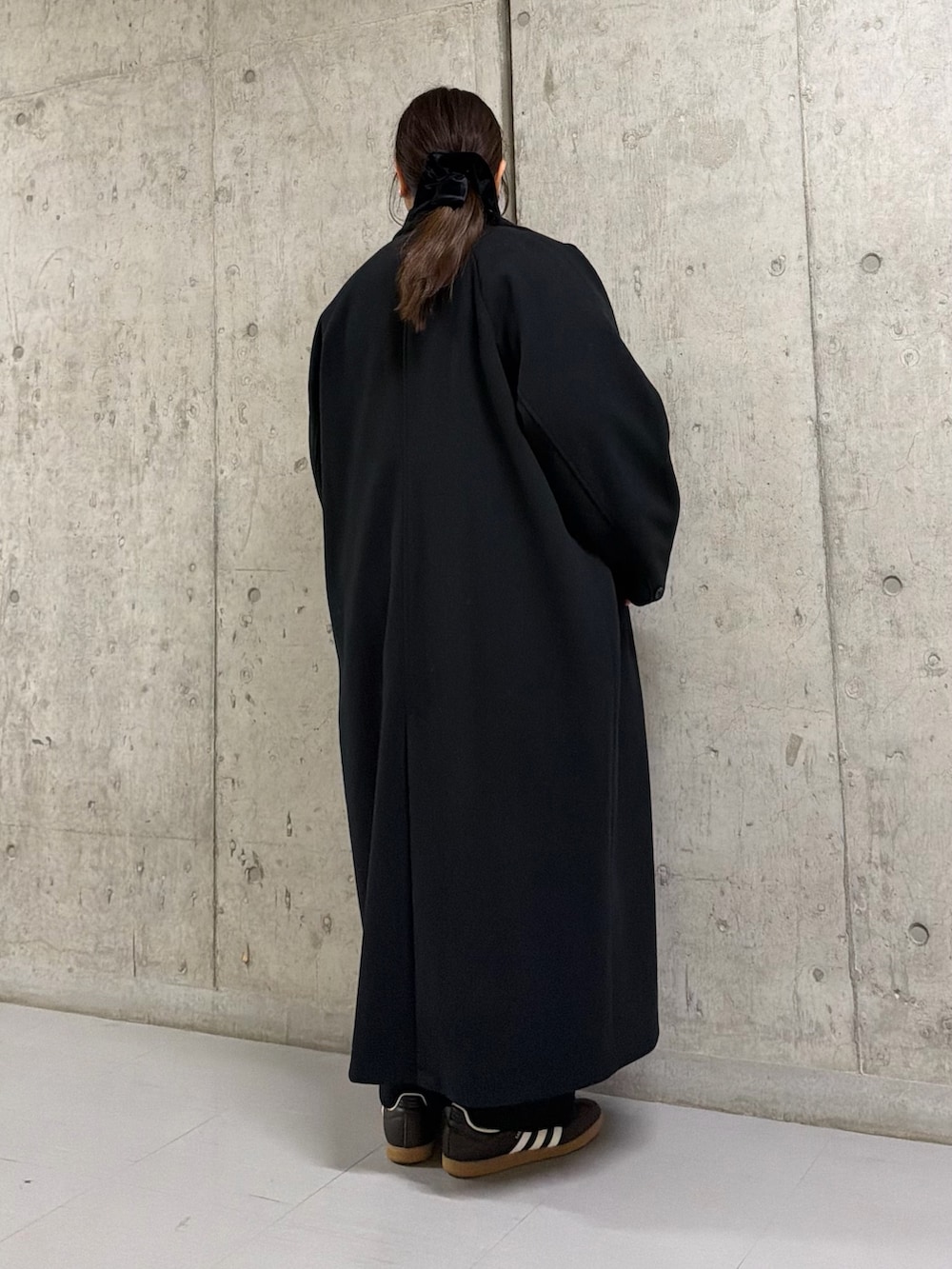 ブラック系のステンカラーコート、ブラウン系のニット/セーター、ブラック系のその他パンツを着用したレディースの冬コーディネートの3枚目の写真