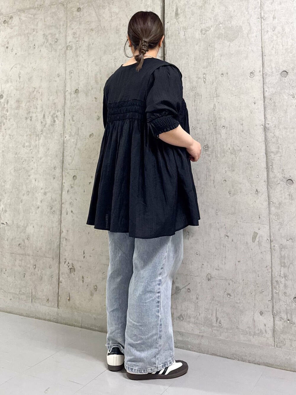 ブルー系のデニムパンツ、ブラック系のワンピースを着用したレディースの春コーディネートの2枚目の写真