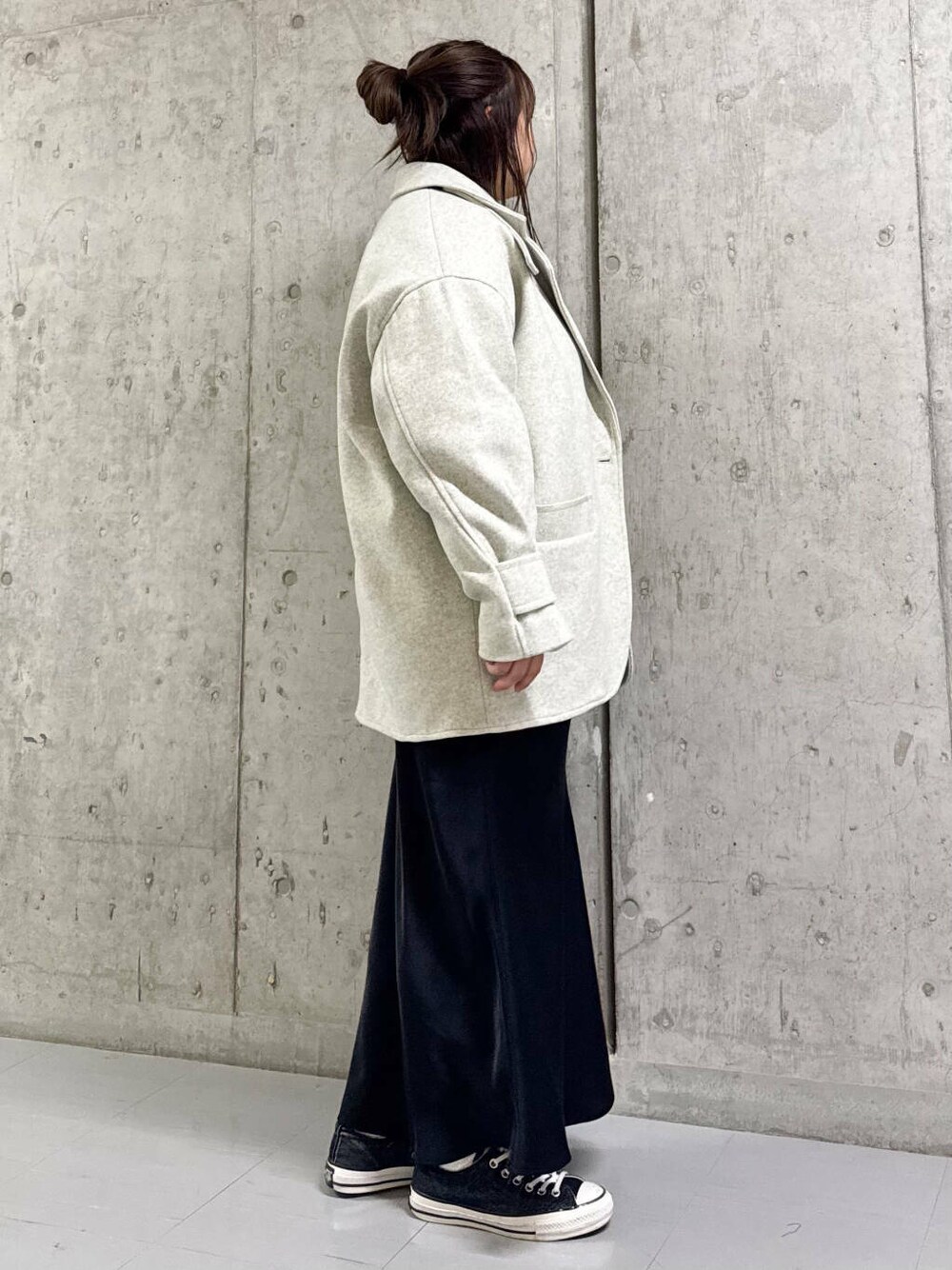 ベージュ系のステンカラーコート、ホワイト系のニット/セーター、ブラック系のスカートを着用したレディースの冬コーディネートの2枚目の写真