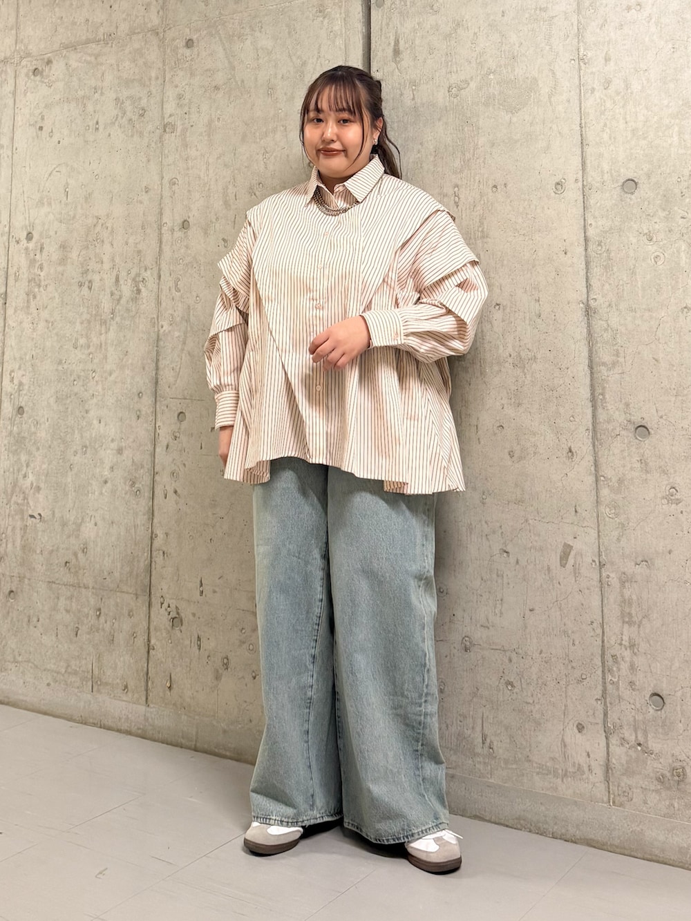 ベージュ系のステンカラーコート、ピンク系のシャツ/ブラウス、ブルー系のデニムパンツを着用したレディースの春コーディネートの2枚目の写真