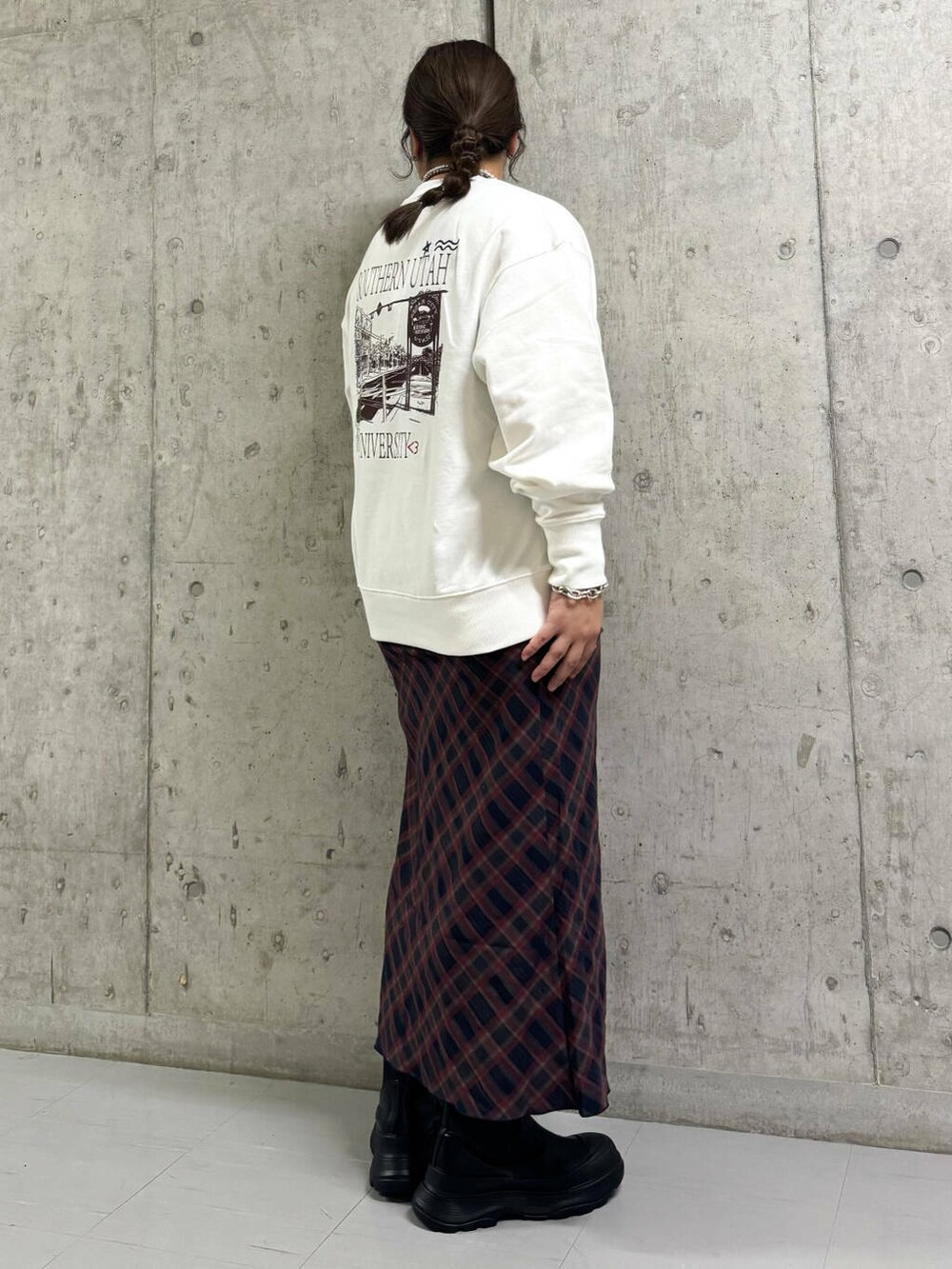 ブルー系のスカート、ブラック系のブーツ、ホワイト系のスウェットを着用したレディースの秋コーディネートの2枚目の写真