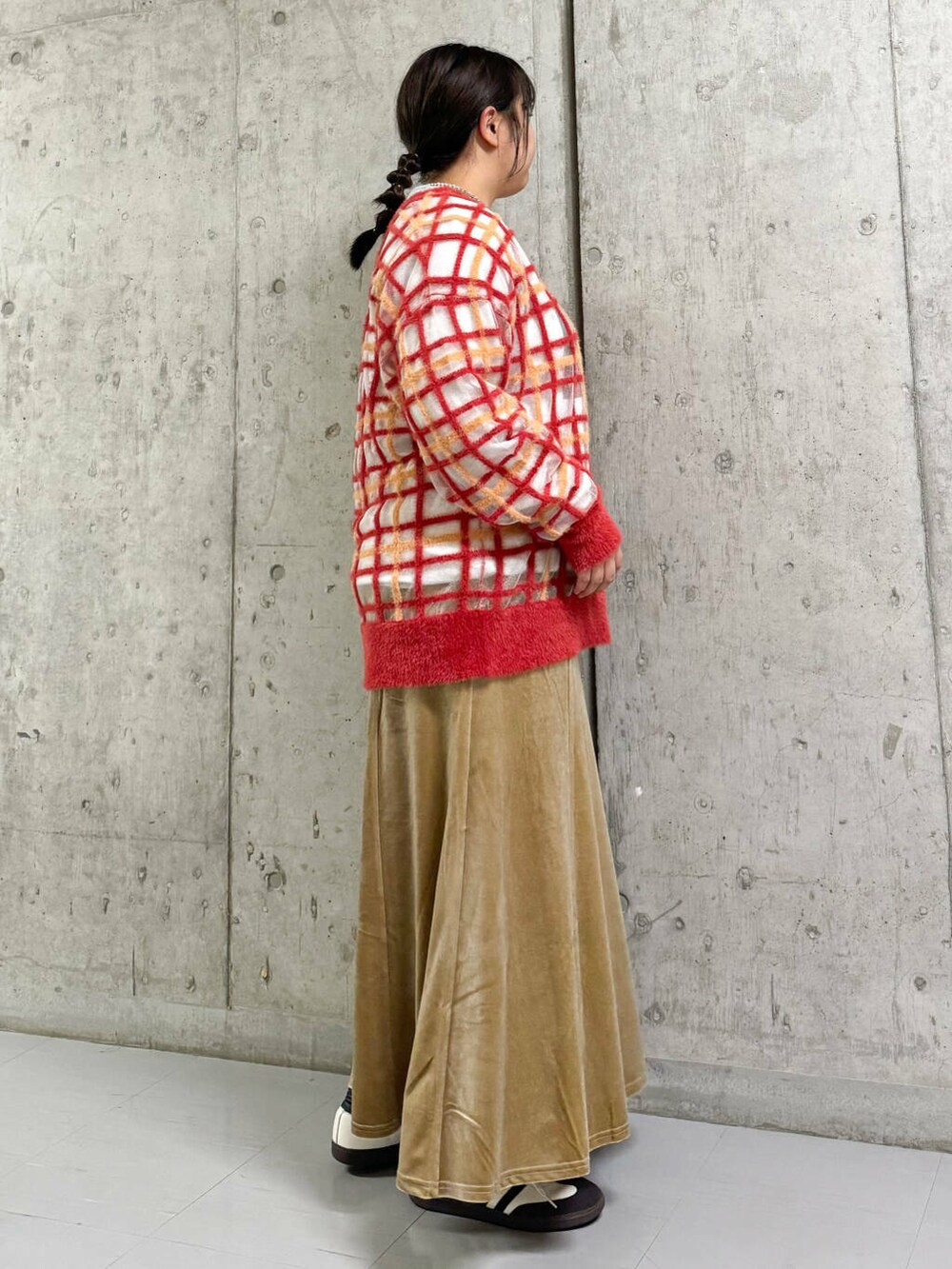 オレンジ系のニット/セーター、グレー系のTシャツ/カットソー、ベージュ系のスカートを着用したレディースの秋コーディネートの2枚目の写真