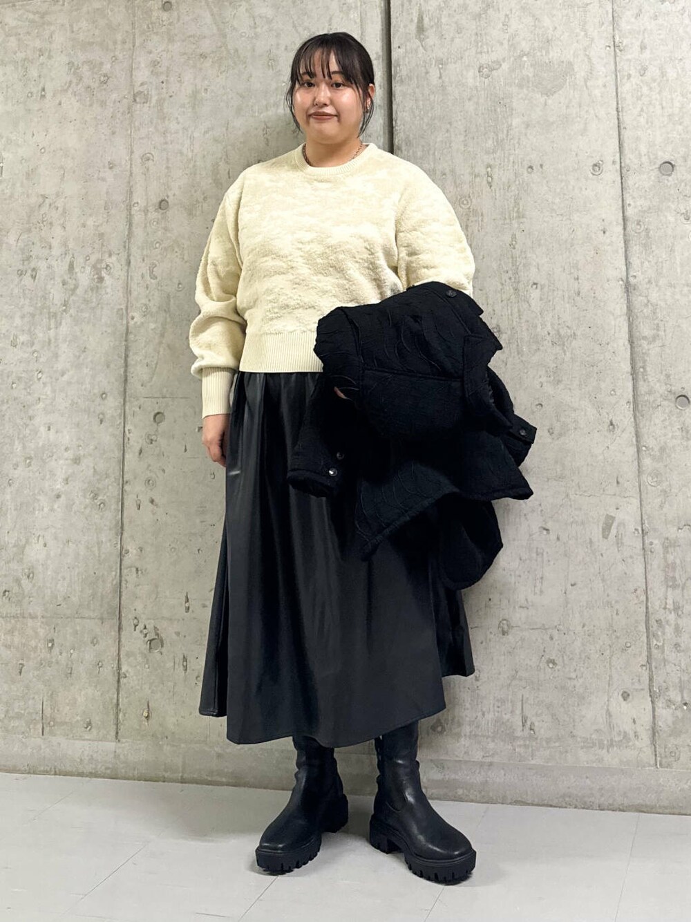 ブラック系のブーツ、ブラック系のスカート、ホワイト系のニット/セーターを着用したレディースの秋コーディネートの2枚目の写真