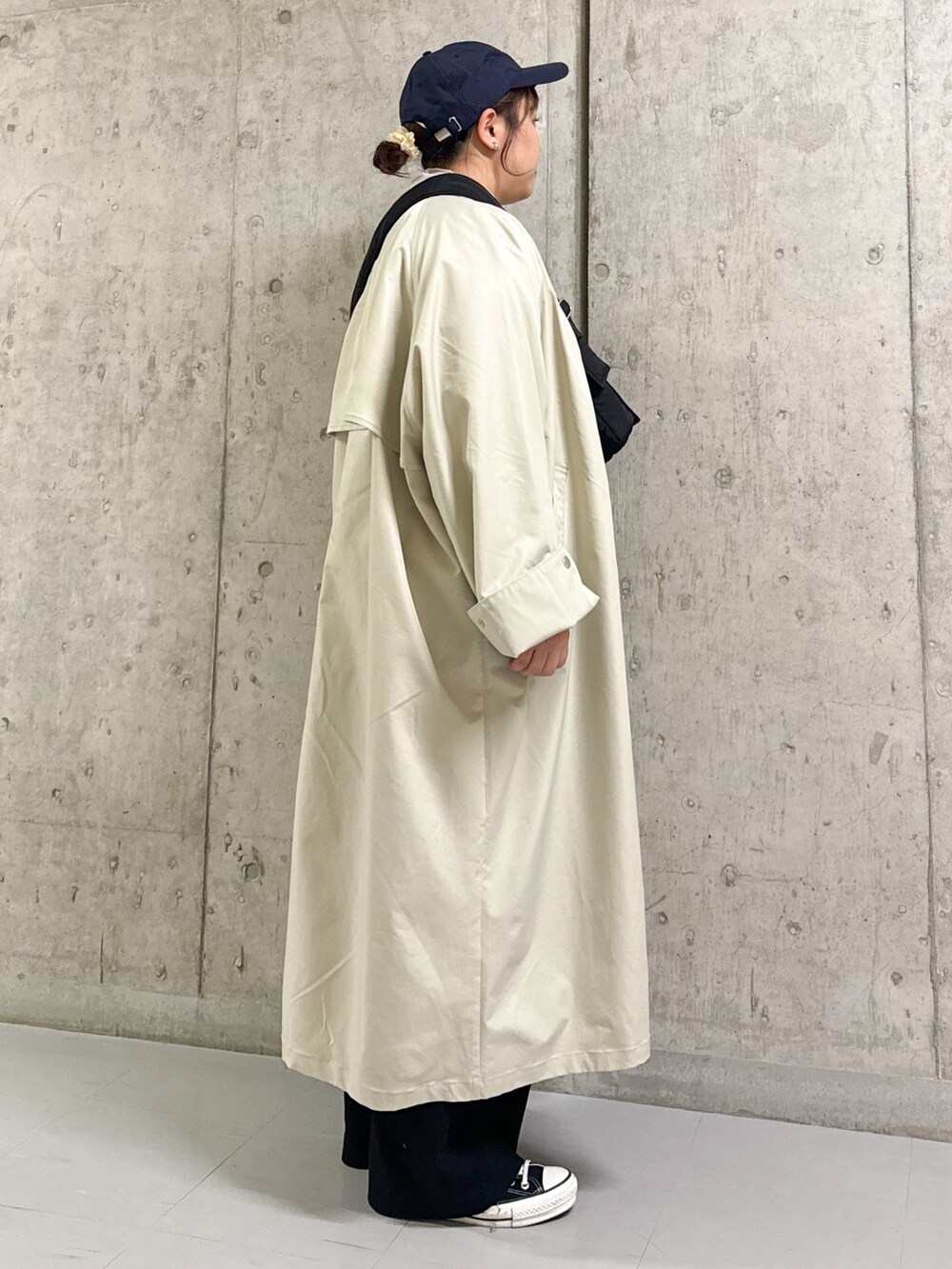 グレー系のステンカラーコート、ブルー系のニット/セーター、ブラック系のショルダーバッグを着用したレディースの春コーディネートの3枚目の写真