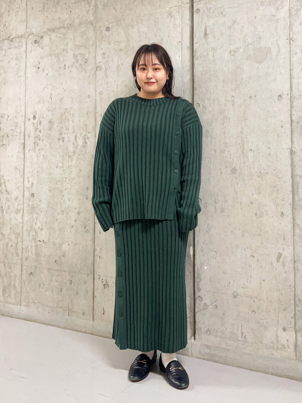 グリーン系のニット/セーター、グレー系のその他アウター、グリーン系のスカートを着用したレディースの冬コーディネートの2枚目の写真