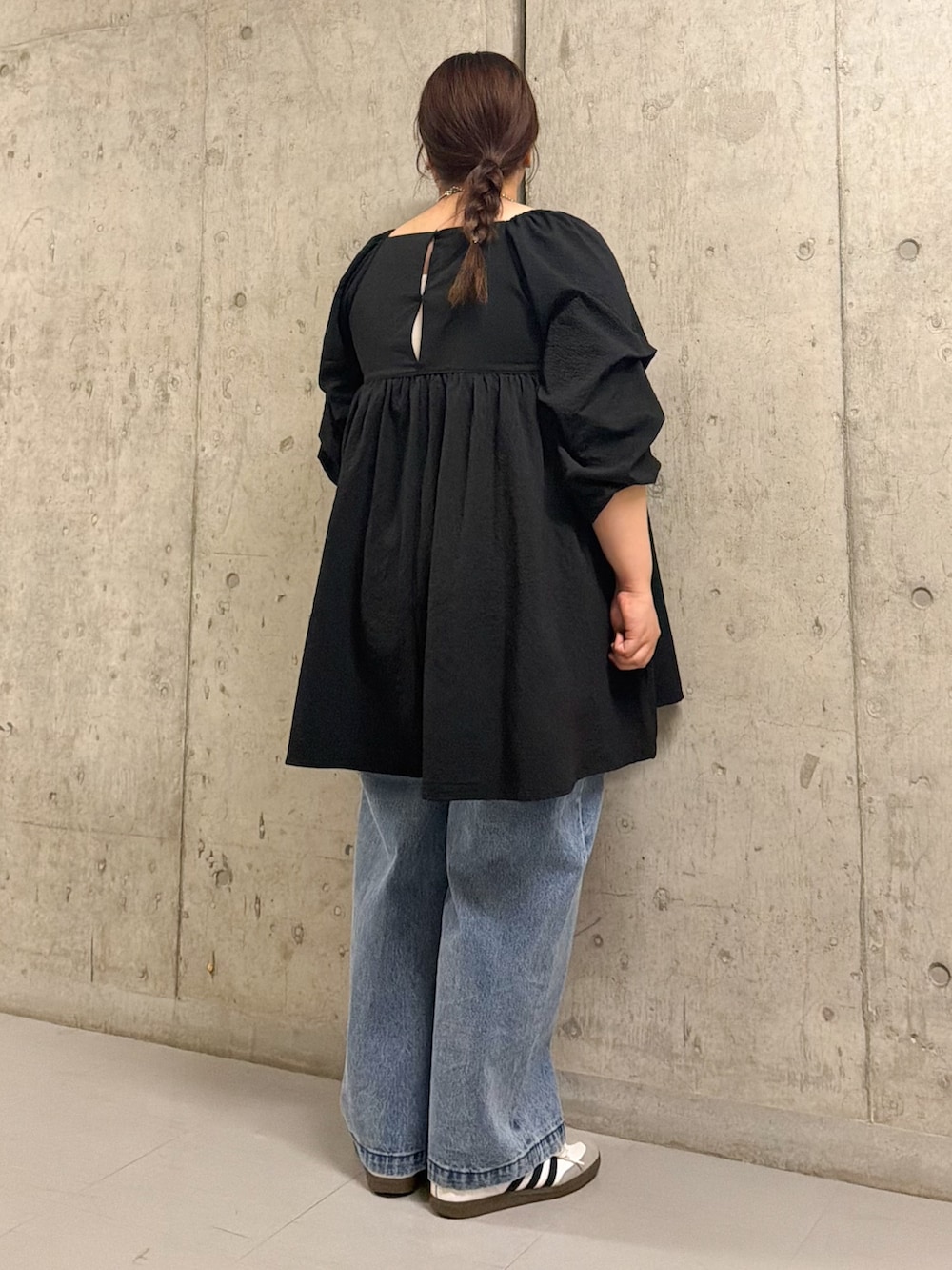 ブラック系のワンピース、ブルー系のデニムパンツを着用したレディースの春コーディネートの3枚目の写真