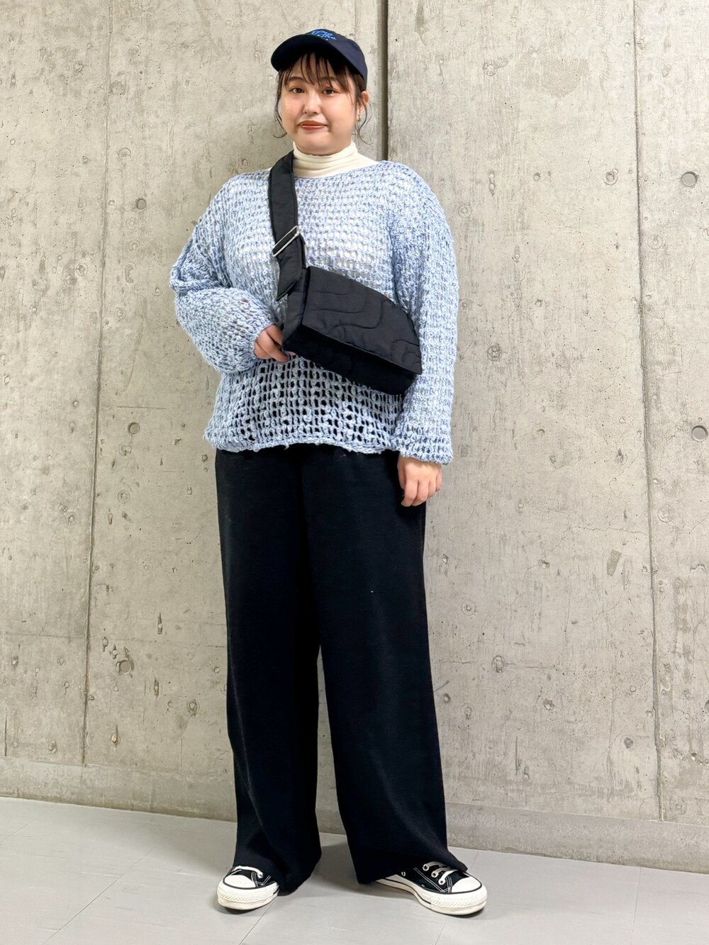 グレー系のステンカラーコート、ブルー系のニット/セーター、ブラック系のショルダーバッグを着用したレディースの春コーディネートの2枚目の写真