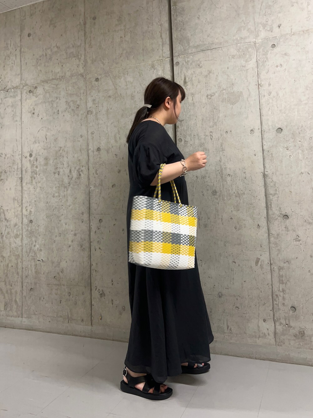 ブラック系のワンピース、イエロー系のトートバッグを着用したレディースの夏コーディネートの2枚目の写真