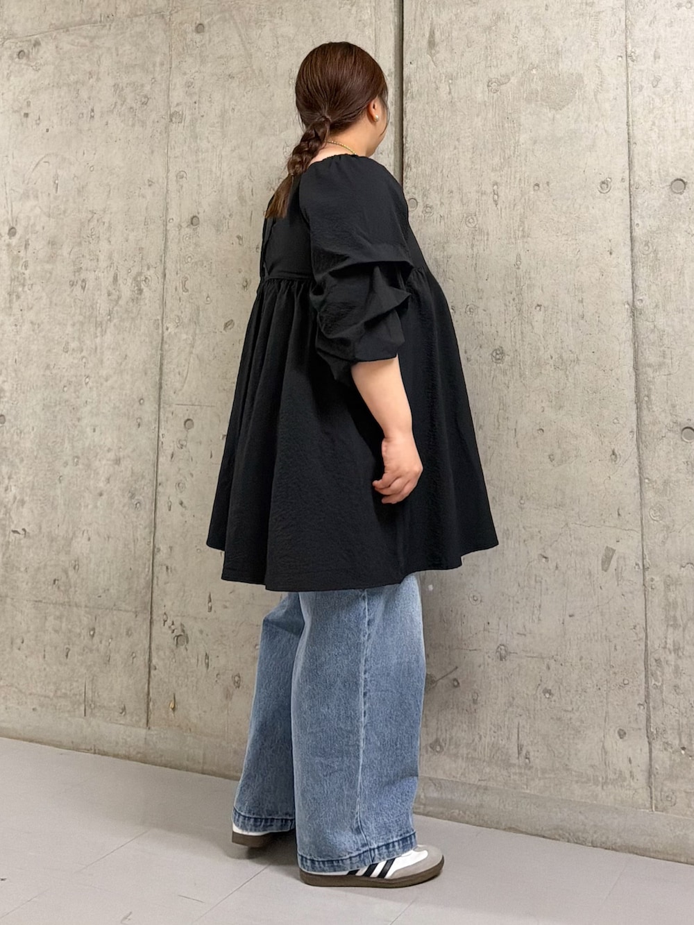 ブラック系のワンピース、ブルー系のデニムパンツを着用したレディースの春コーディネートの2枚目の写真