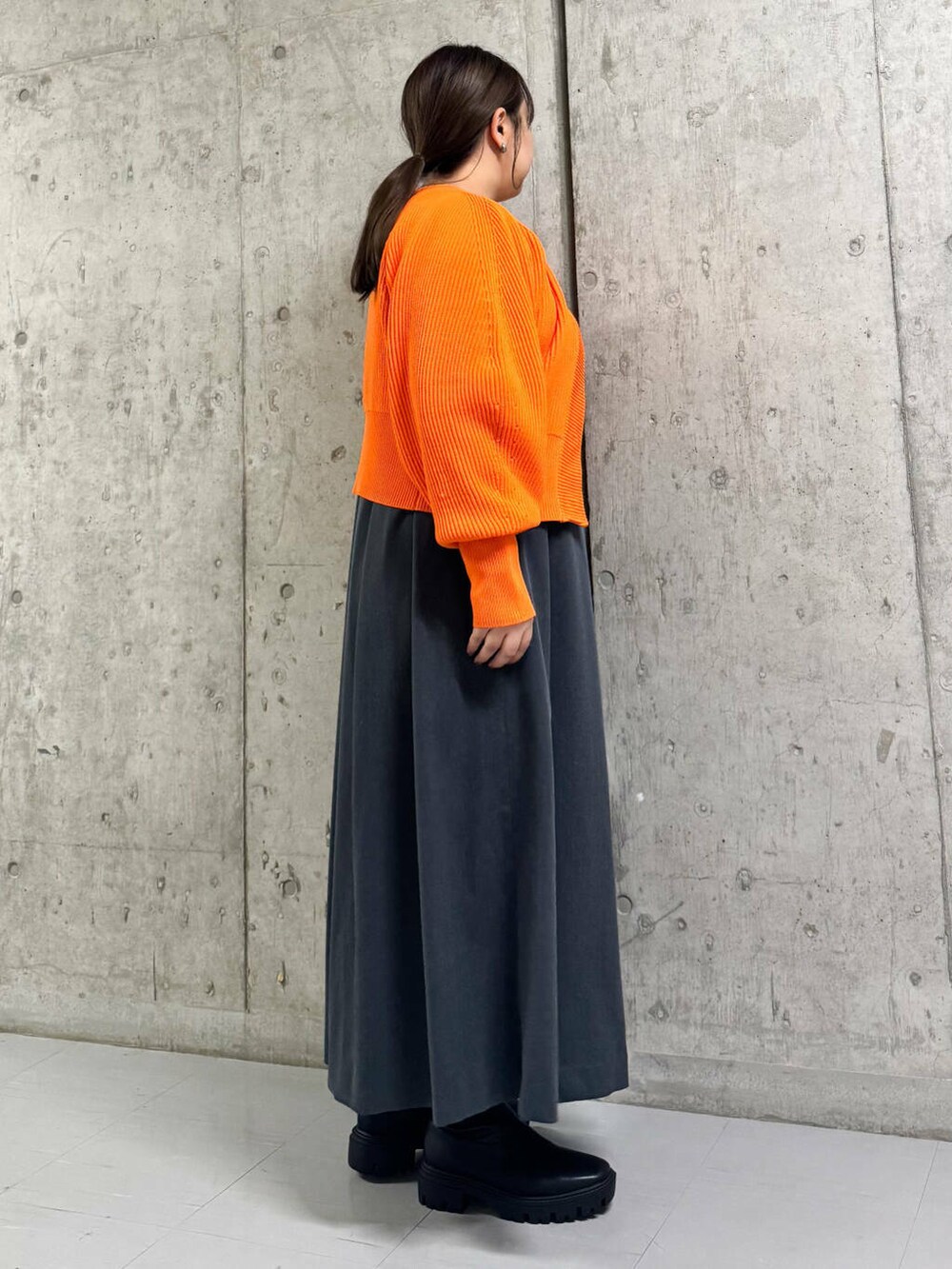 ブラック系のブーツ、グレー系のワンピース、オレンジ系のカーディガン/ボレロを着用したレディースの冬コーディネートの2枚目の写真