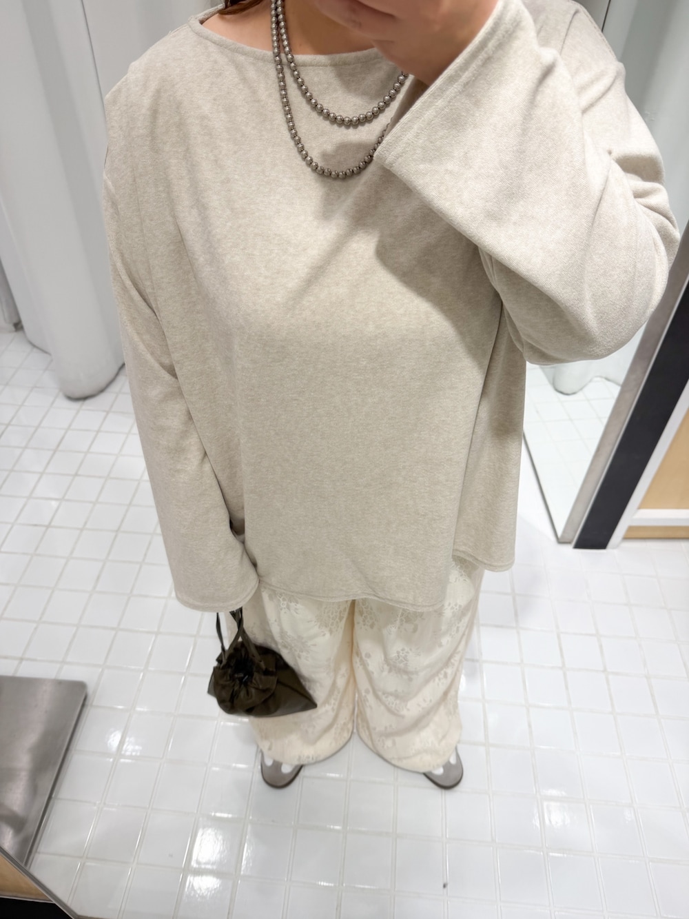 ベージュ系のTシャツ/カットソー、ホワイト系のその他パンツ、グリーン系のショルダーバッグを着用したレディースの冬コーディネートの2枚目の写真