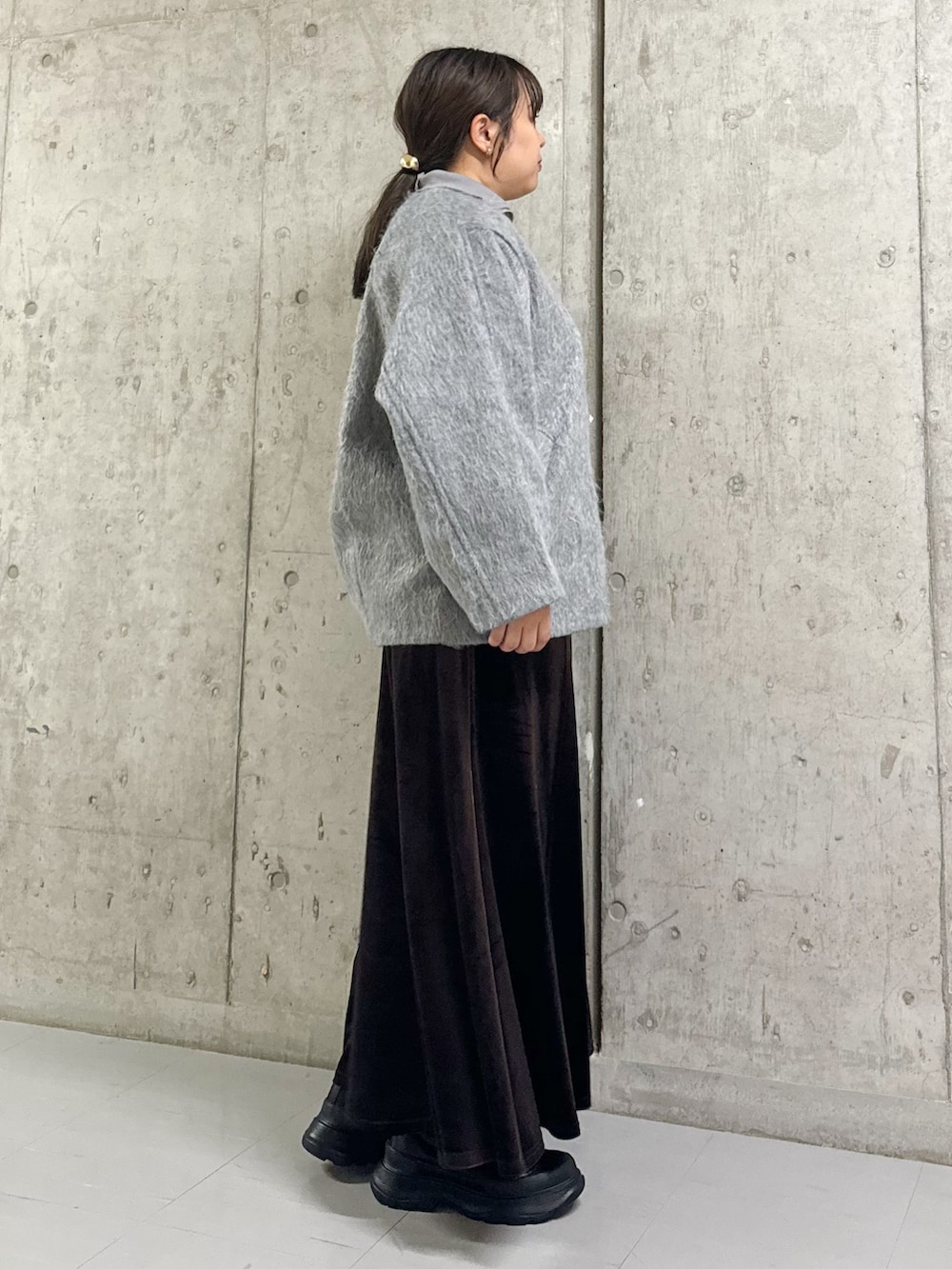 グレー系のその他アウター、ブラウン系のスカート、ブラック系のブーツを着用したレディースの冬コーディネートの2枚目の写真