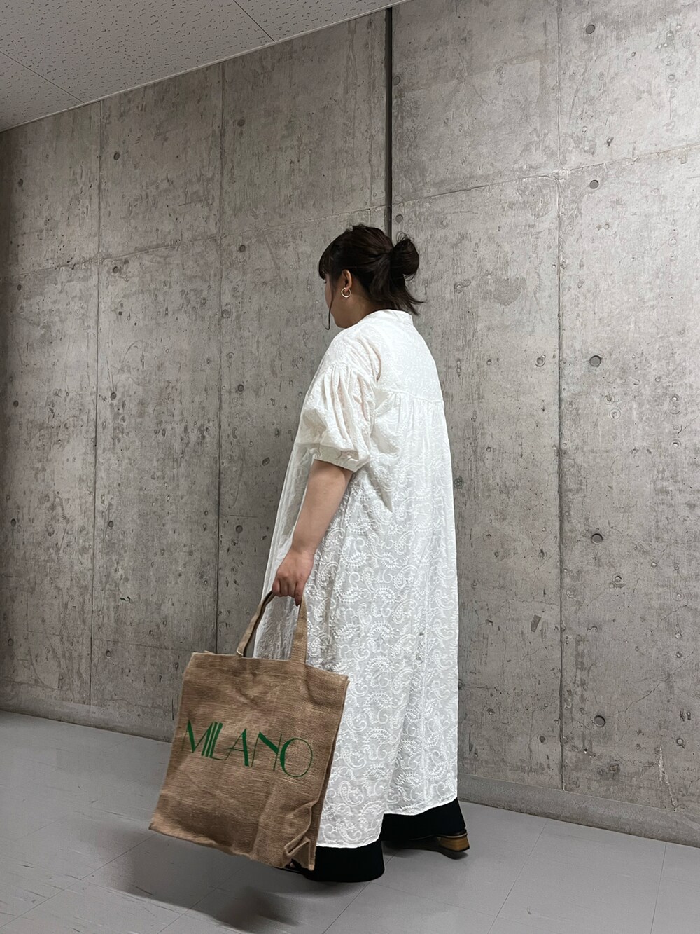 ホワイト系のワンピース、ブラック系のサンダル、ベージュ系のバッグを着用したレディースの春コーディネートの3枚目の写真