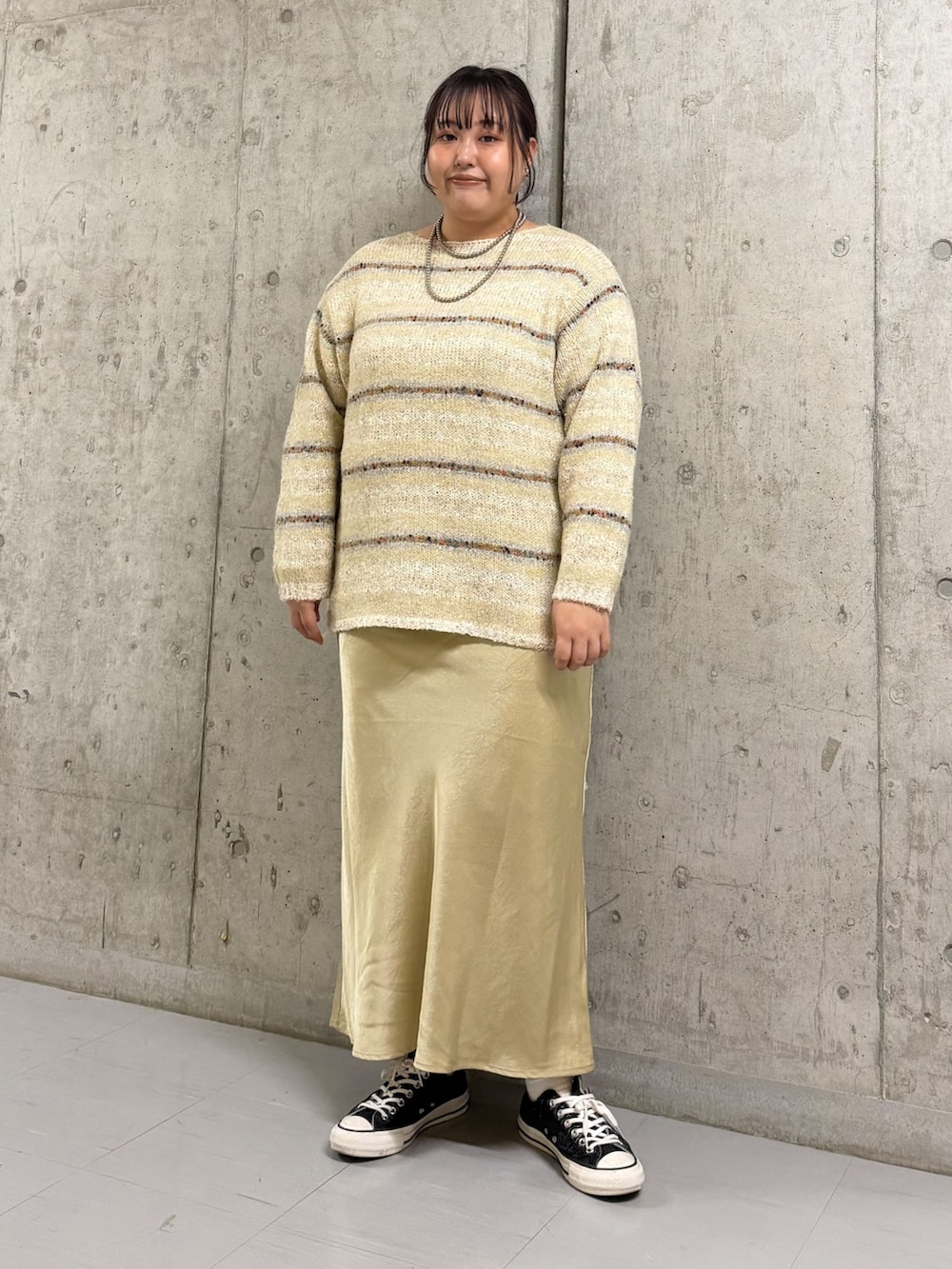 イエロー系のダウンジャケット/コート、ホワイト系のニット/セーター、パープル系のスカートを着用したレディースの秋コーディネートの2枚目の写真