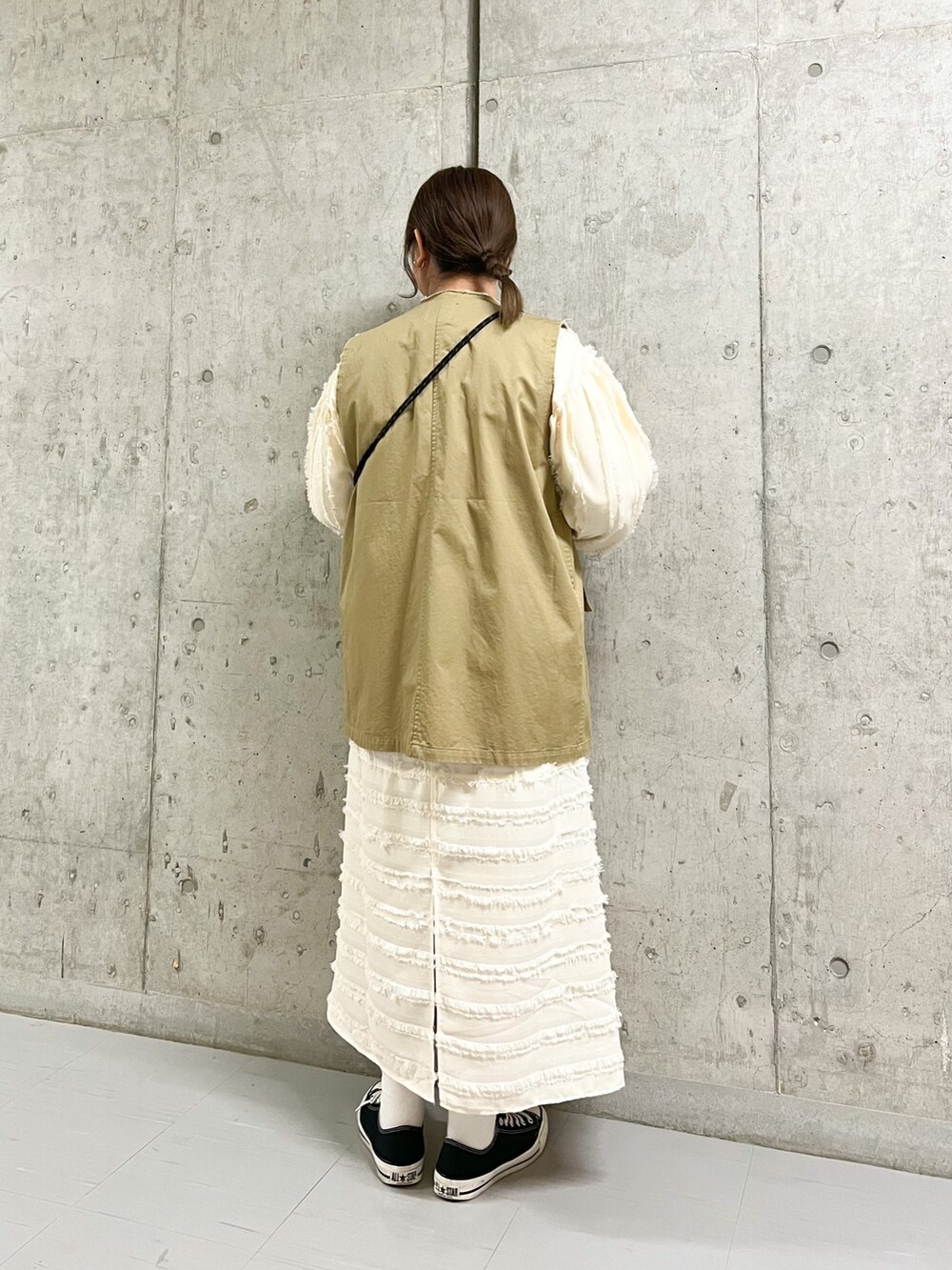 ベージュ系のベスト、ブラック系のショルダーバッグ、ホワイト系のワンピースを着用したレディースの春コーディネートの3枚目の写真