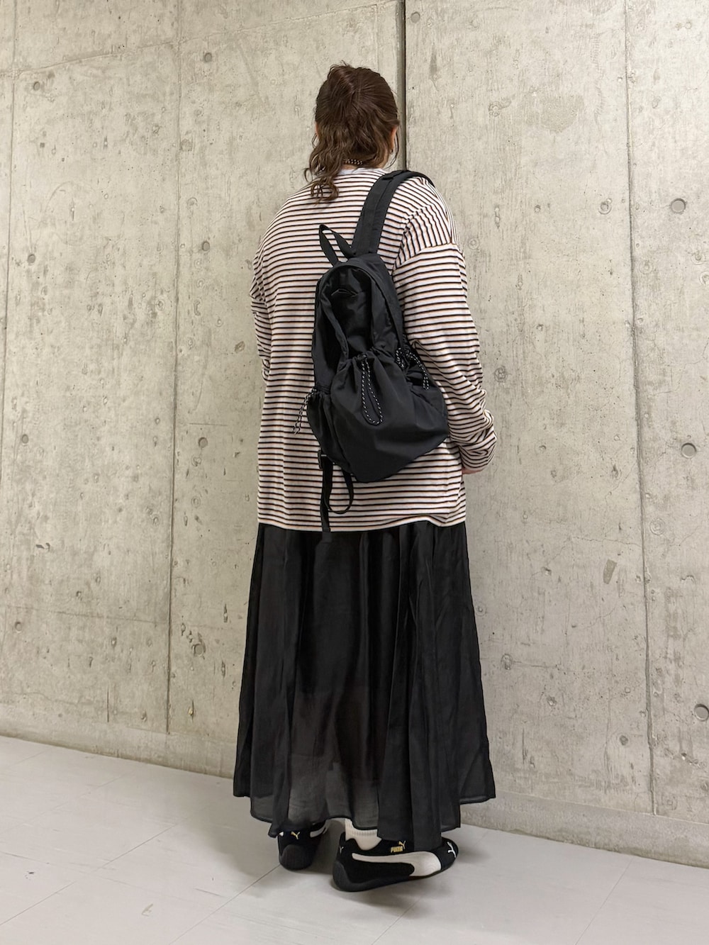 グレー系のニット/セーター、ブラック系のバックパック/リュック、ブラック系のスカートを着用したレディースの春コーディネートの3枚目の写真