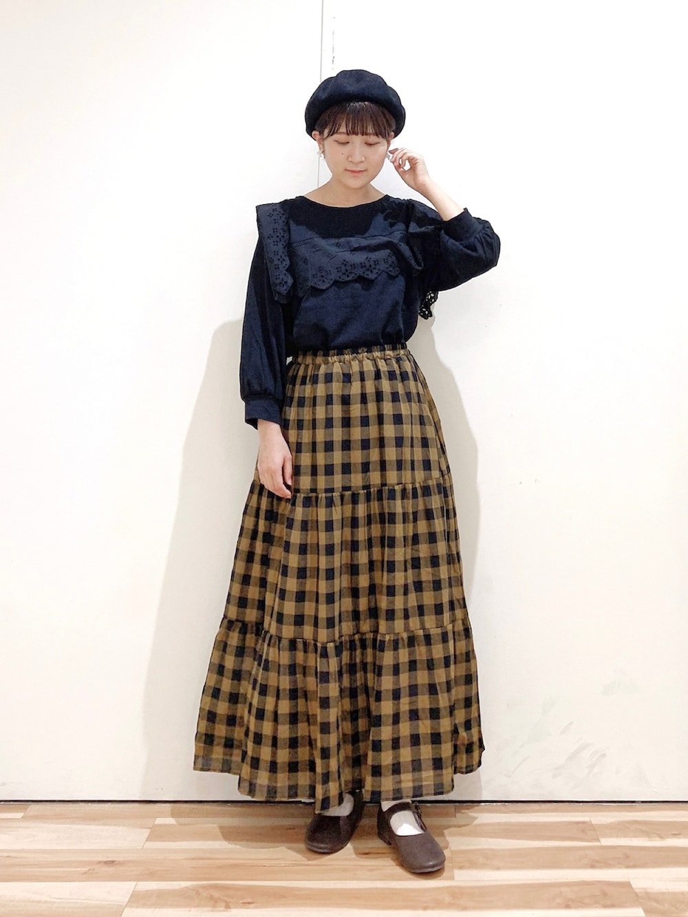 ブラック系のTシャツ/カットソー、ブラウン系のパンプス、イエロー系のスカートを着用したレディースの秋コーディネートの2枚目の写真