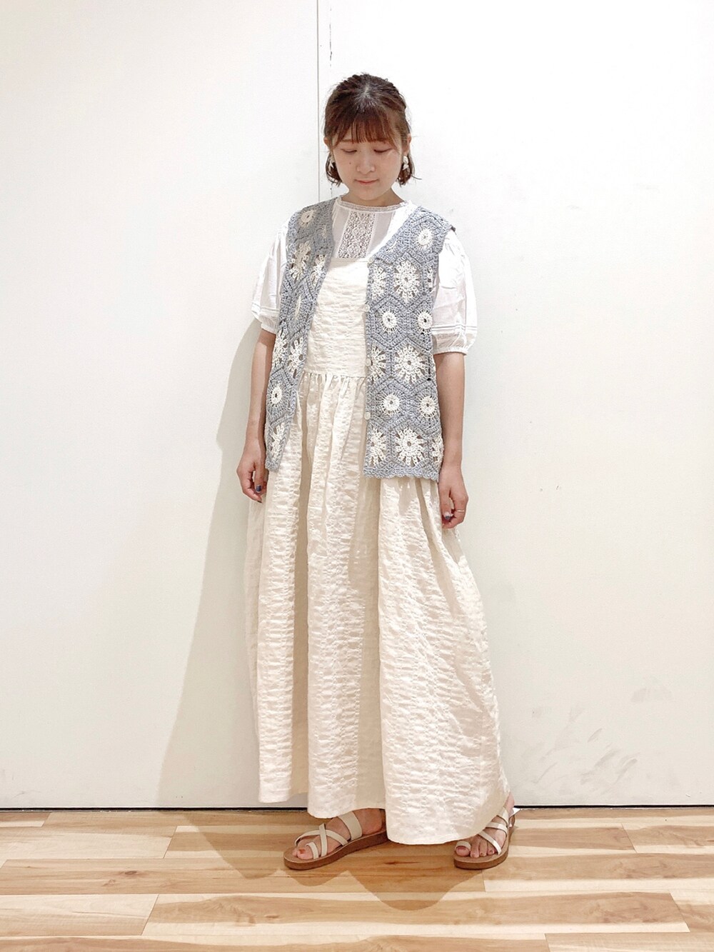 ホワイト系のサンダル、ベージュ系のワンピース、グレー系のベストを着用したレディースの夏コーディネートの2枚目の写真