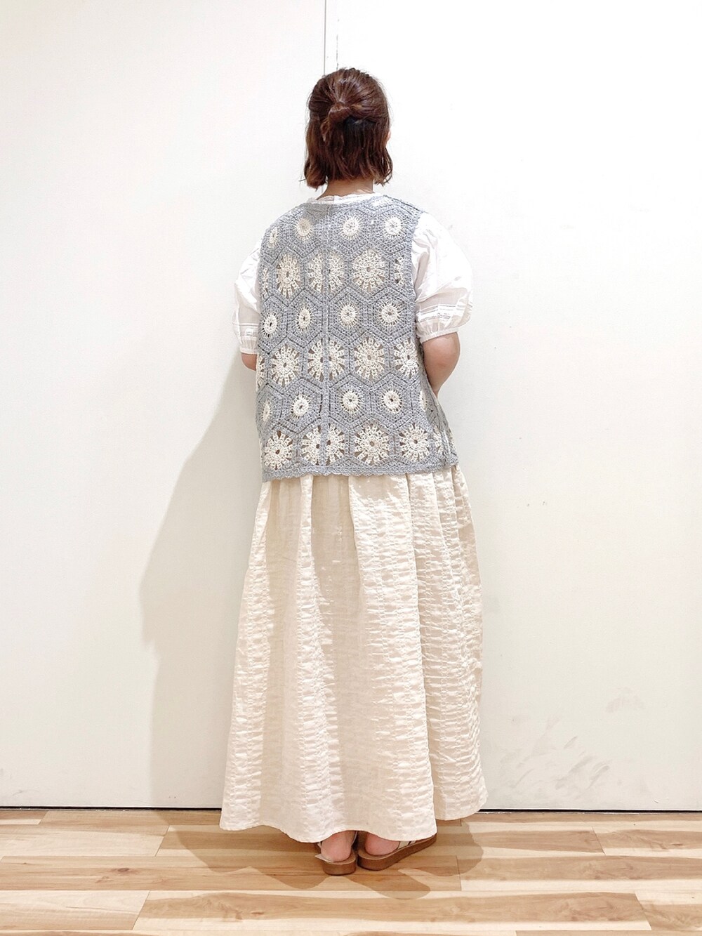 ホワイト系のサンダル、ベージュ系のワンピース、グレー系のベストを着用したレディースの夏コーディネートの4枚目の写真