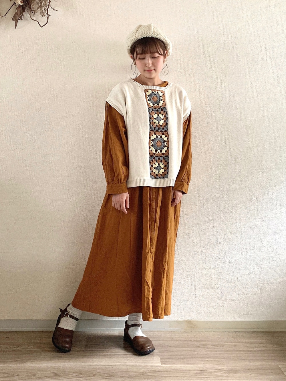 ブラウン系のシューズ、イエロー系のワンピース、ホワイト系のベストを着用したレディースの冬コーディネートの2枚目の写真