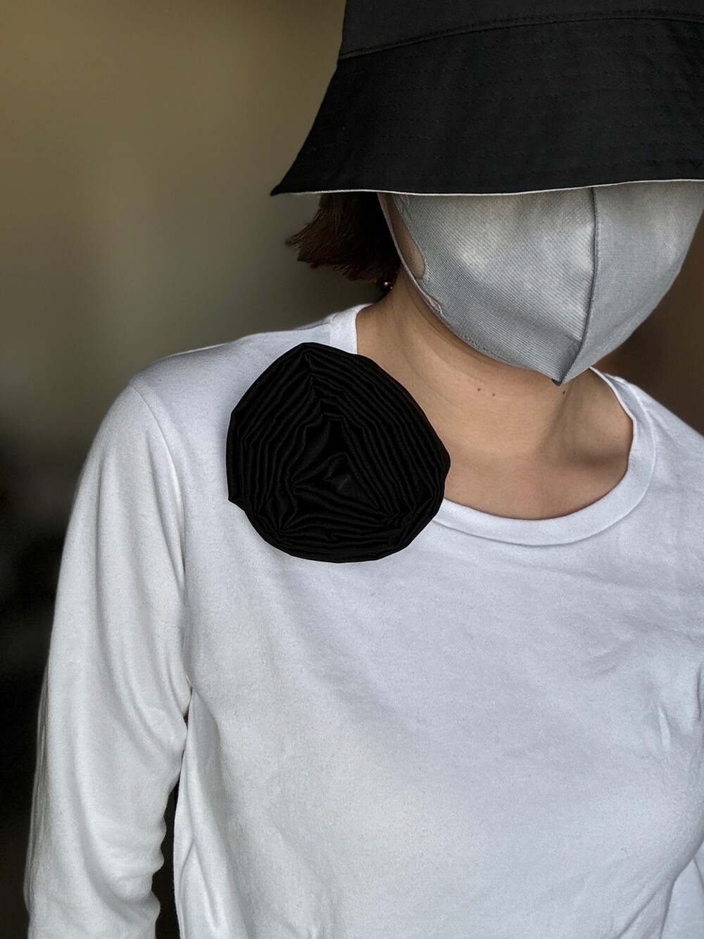 ホワイト系のTシャツ/カットソー、ブラック系のダウンジャケット/コート、ブラック系のスニーカーを着用したレディースの春コーディネートの2枚目の写真