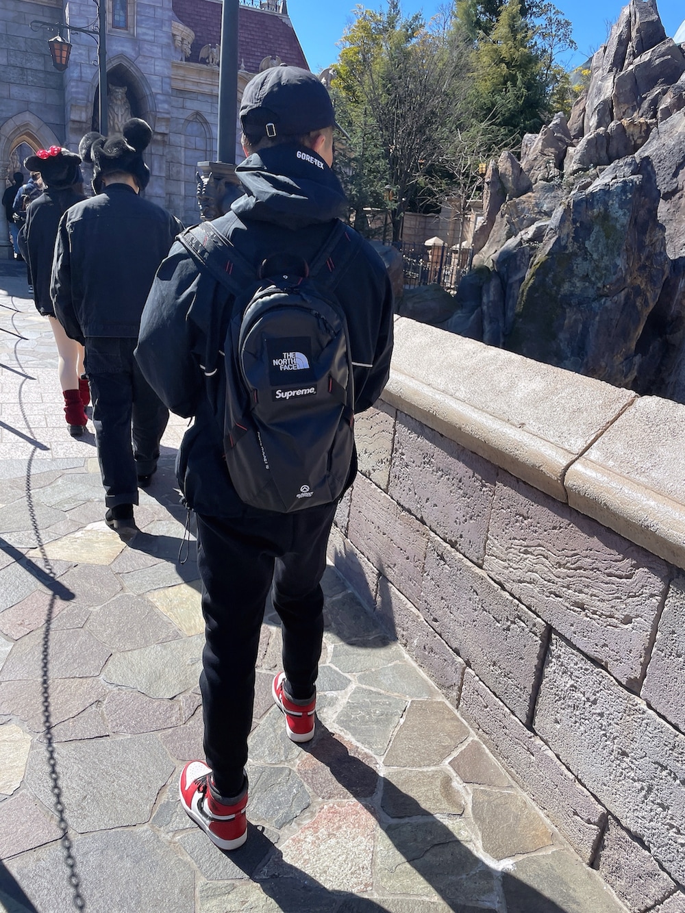 ブラック系のマウンテンパーカー、ブラック系のスウェットパンツ、レッド系のスニーカーを着用したメンズの春コーディネートの2枚目の写真