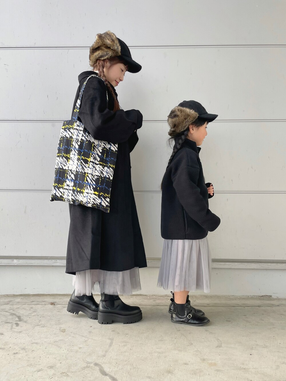 ブラック系のトートバッグ、ブラック系のステンカラーコート、グレー系のスカートを着用したレディースの秋コーディネートの3枚目の写真