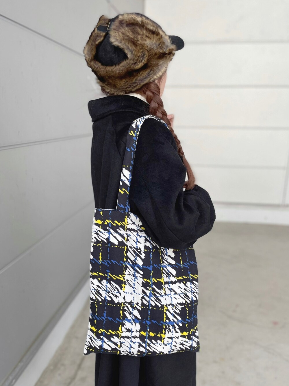 ブラック系のトートバッグ、ブラック系のステンカラーコート、グレー系のスカートを着用したレディースの秋コーディネートの4枚目の写真