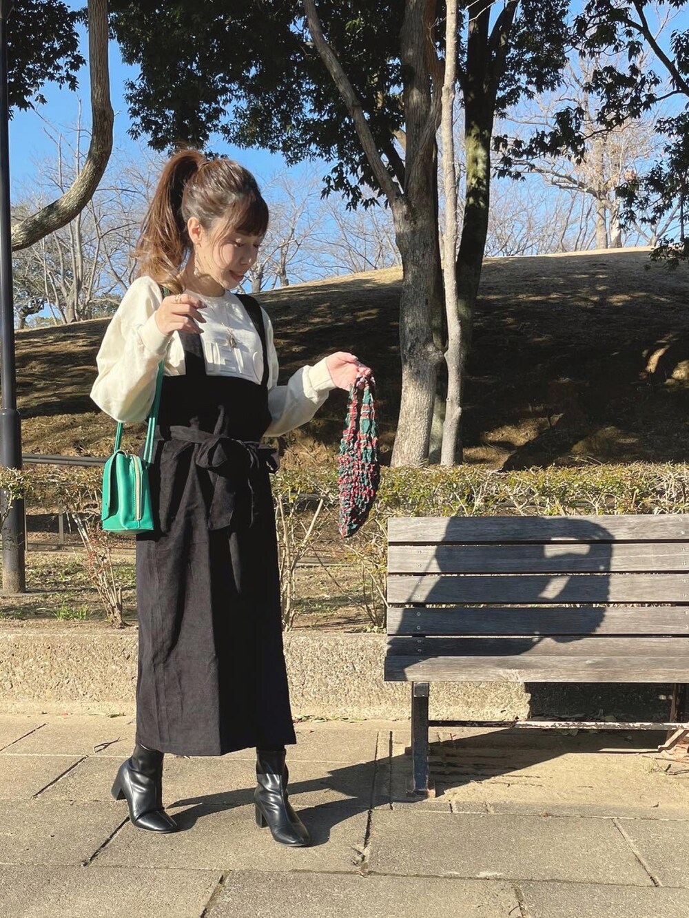 ブラック系のブーツ、ブラック系のジャンパースカート、ホワイト系のスウェットを着用したレディースの冬コーディネートの2枚目の写真