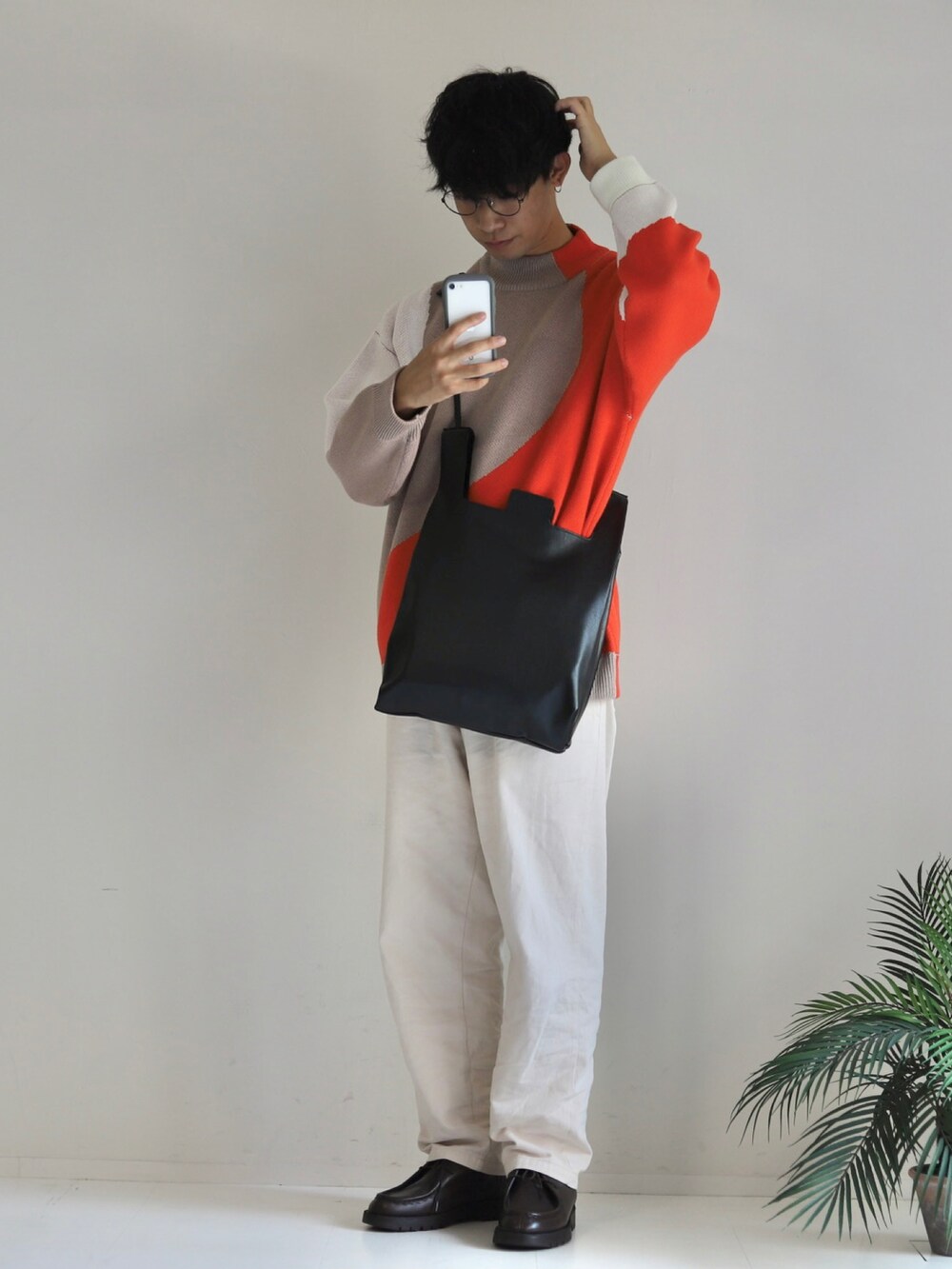 ブラック系のショルダーバッグ、オレンジ系のニット/セーター、ホワイト系のその他パンツを着用したメンズの秋コーディネートの2枚目の写真